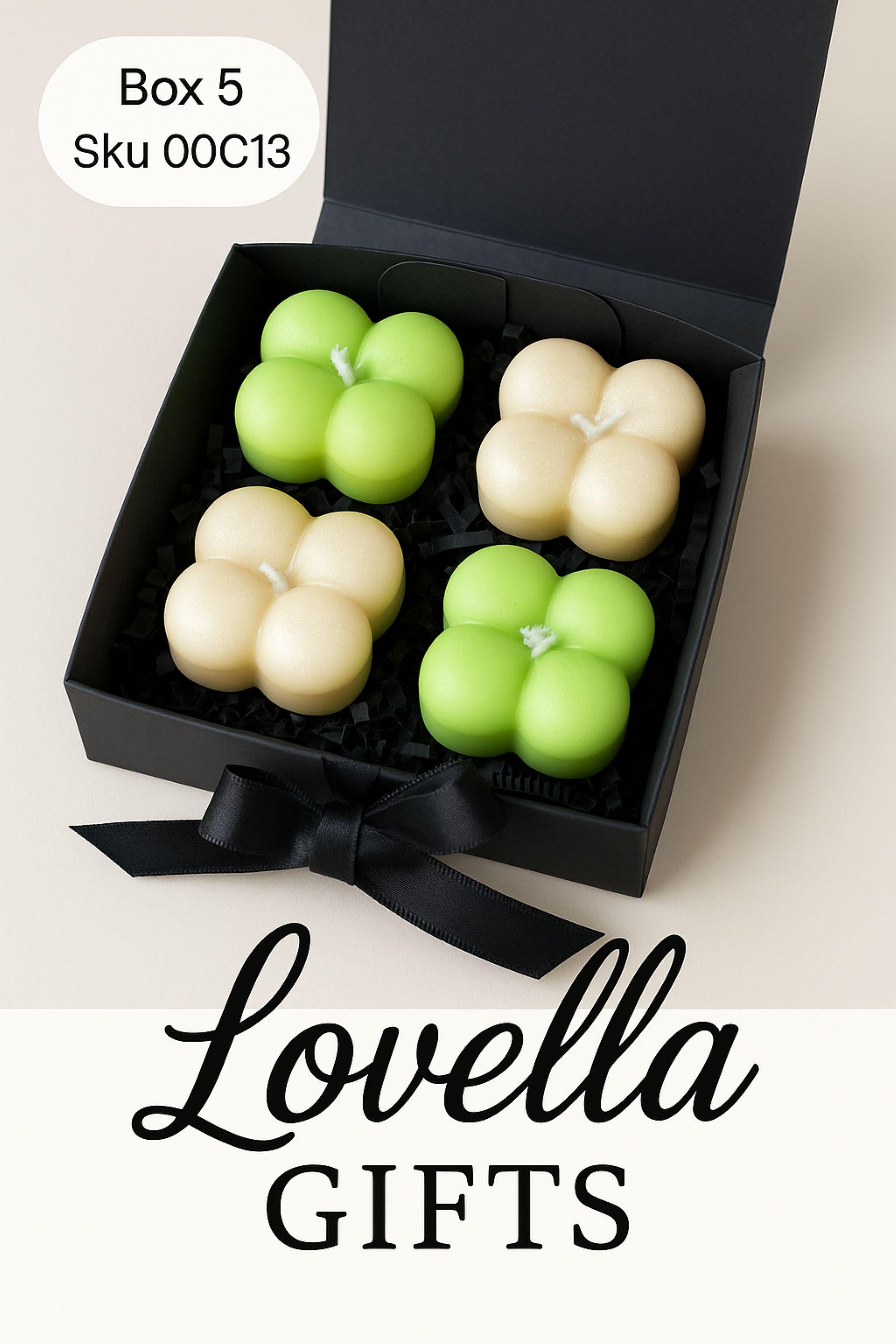 Christmas bubble candle gift box with four pastel mini bubble candles in a black box with ribbon, styled with festive greenery and ornaments. Cozy holiday spa gift set and small Christmas present for her.