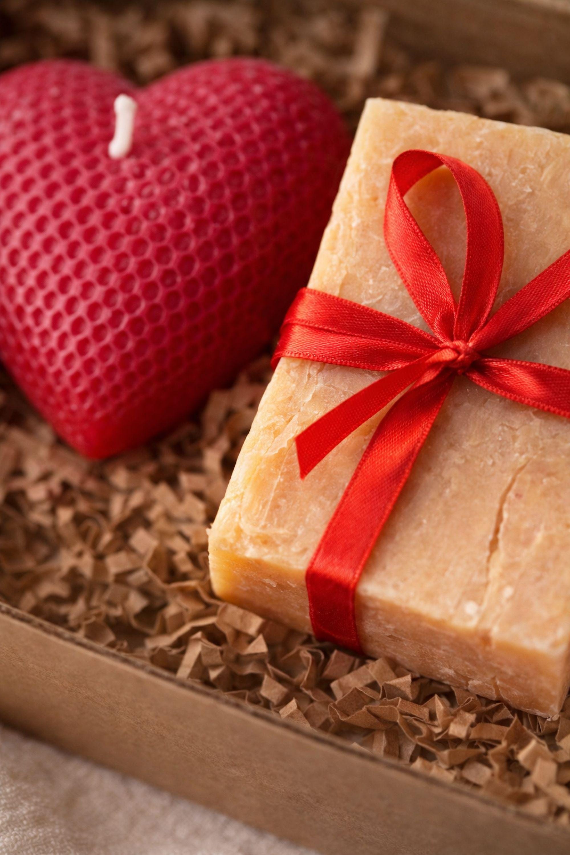 Cozy Valentine gift box with handmade soap tied with red ribbon, heart shaped candle, scented candle with dried flowers, bath salts in glass tubes, and knitted washcloth arranged in kraft gift box. Romantic self care gift for her, comfort care package, handmade Valentine’s Day gift, thinking of you box, ready to gift cozy relaxation set.