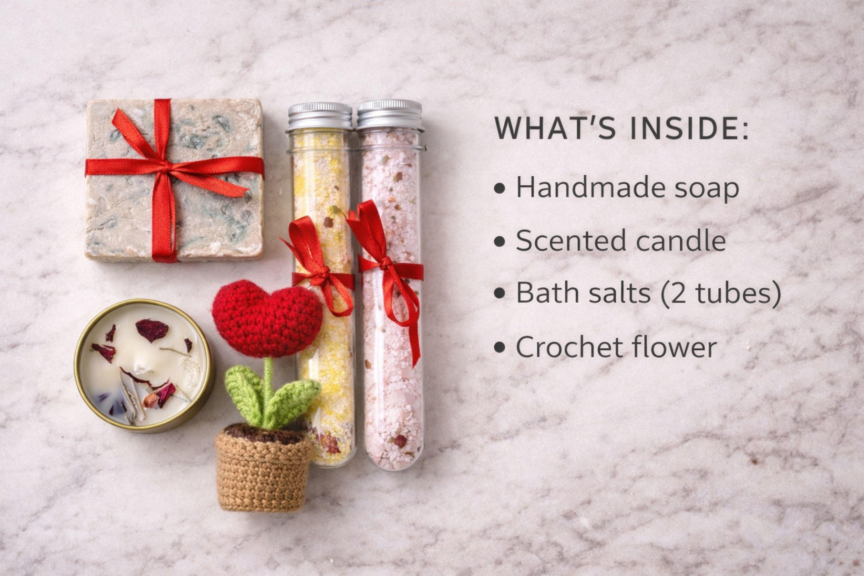 Handmade crochet flower gift box with crochet flower in a pot, handmade soap, botanical candle in a tin, and two bath salt tubes arranged in a black gift box. Thoughtful comfort gift designed to show care and appreciation. Perfect thinking of you gift, friendship gift, or unique handmade present for her, beautifully packaged and ready to give.