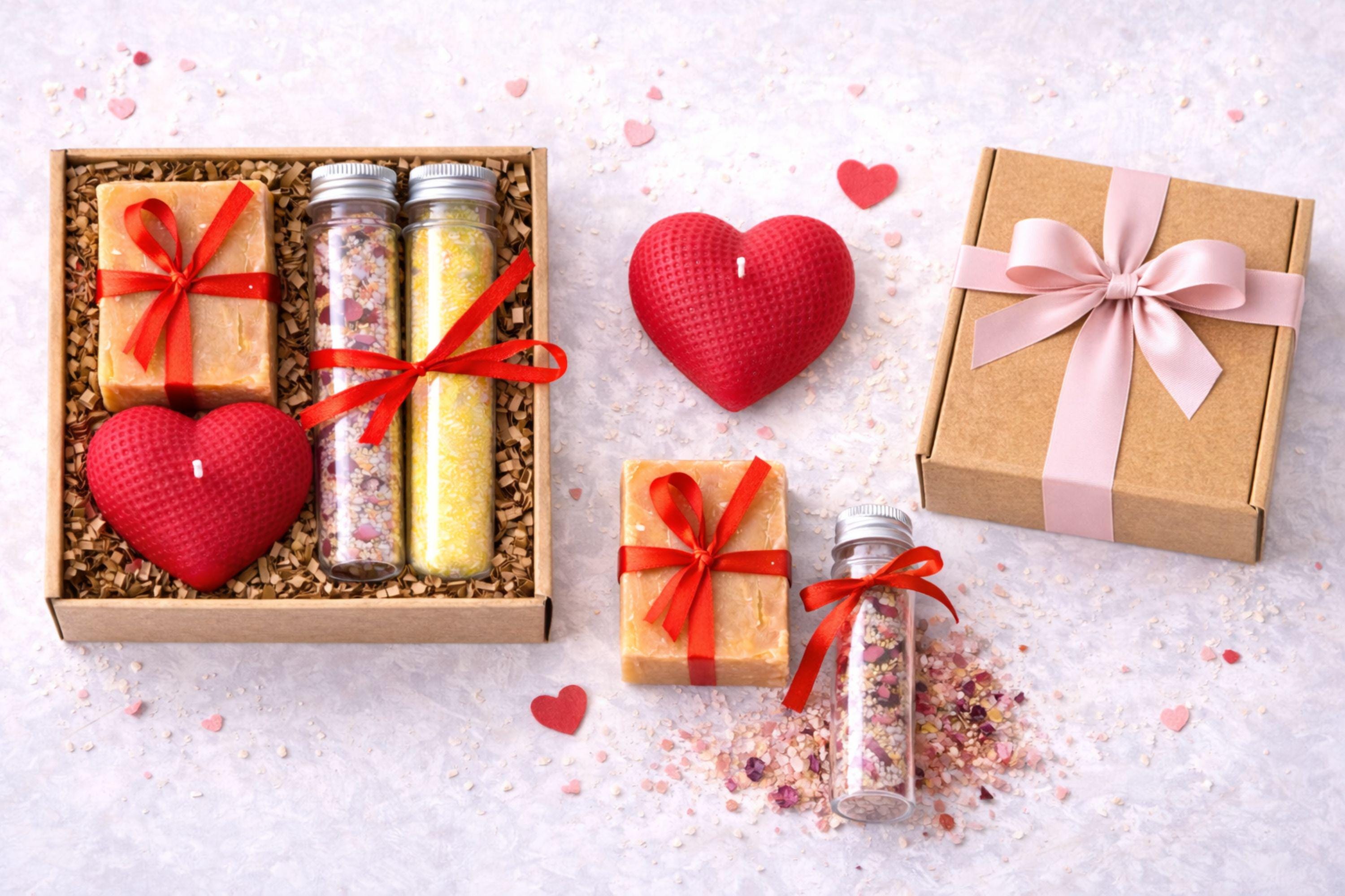 Open kraft gift box showing the exact contents of this romantic gift for her, including a handmade heart candle, natural soap with red ribbon, and two bath salt tubes. The arrangement accurately represents the real box size and items included. This handmade love gift set is designed to provide a clear and honest view of what is included, perfect for buyers searching for a romantic candle and soap gift box.