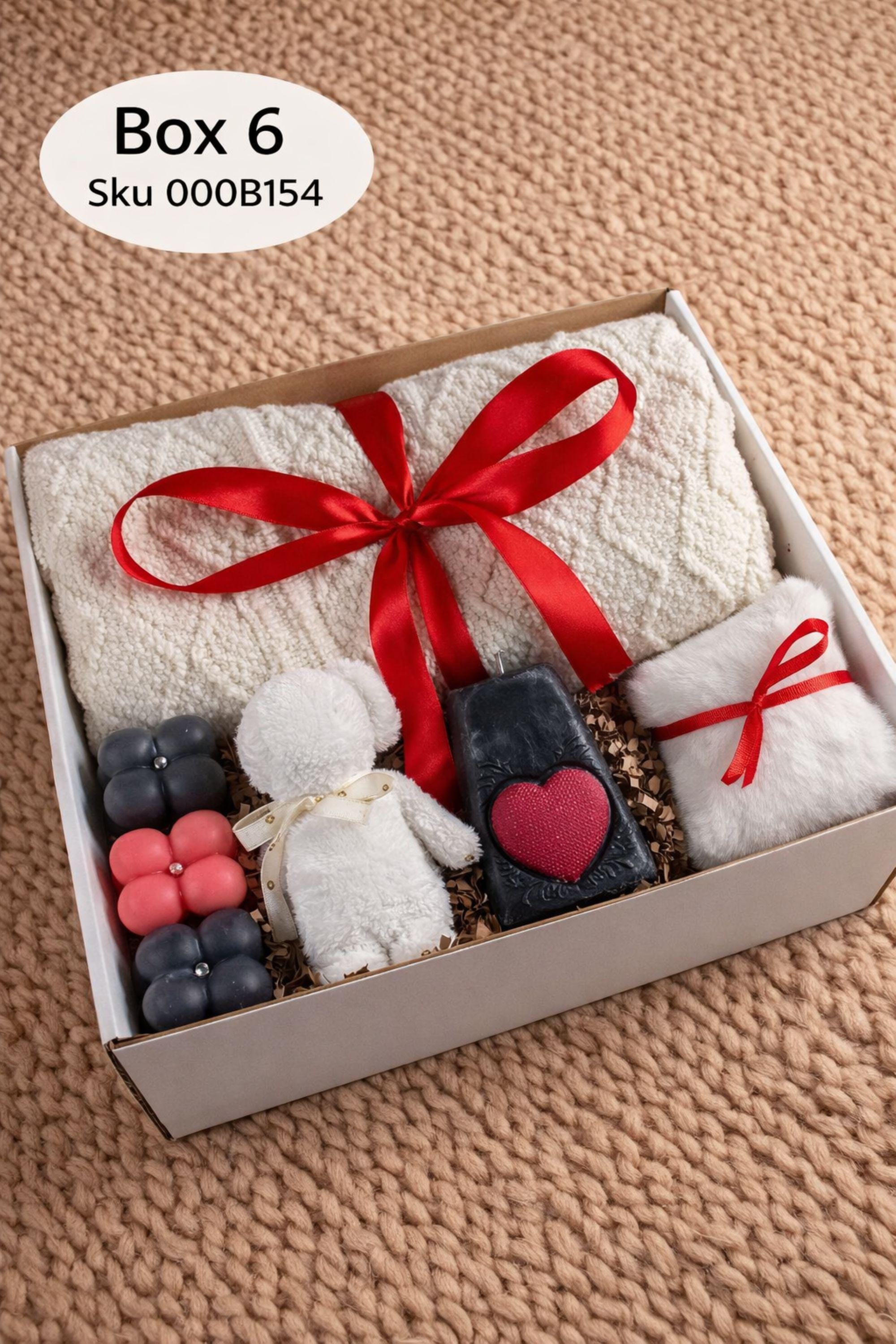 Large cozy blanket gift box with handmade candles, soap, plush socks, and soft bear-shaped face cloth arranged in a white gift box. A rolled cream blanket tied with red ribbon sits at the back, paired with a heart candle, pillar candle, artisan soap, crochet heart and flower, and cozy accessories. A warm self care comfort gift ideal for Valentine’s Day, birthdays, or sending love and relaxation.