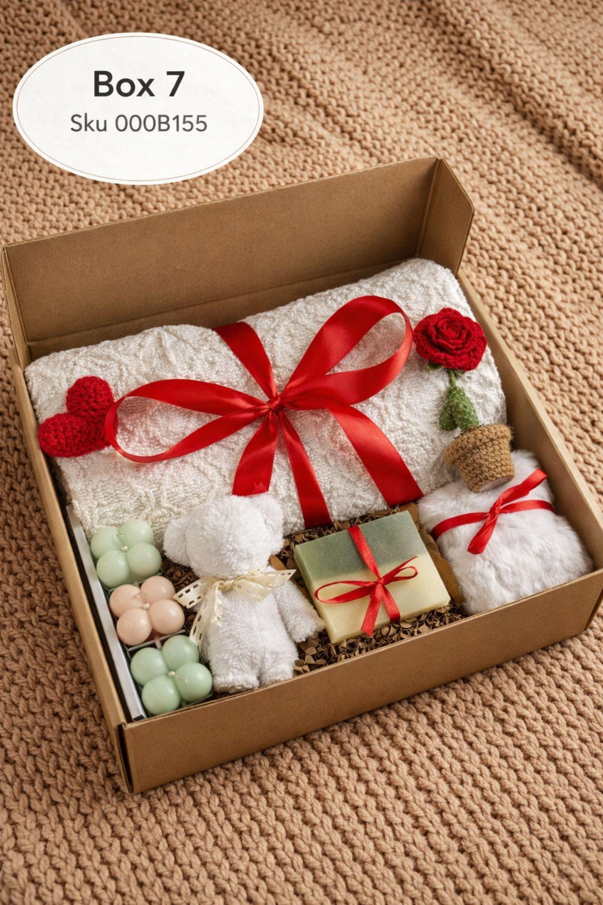 Large cozy blanket gift box with handmade candles, soap, plush socks, and soft bear-shaped face cloth arranged in a white gift box. A rolled cream blanket tied with red ribbon sits at the back, paired with a heart candle, pillar candle, artisan soap, crochet heart and flower, and cozy accessories. A warm self care comfort gift ideal for Valentine’s Day, birthdays, or sending love and relaxation.