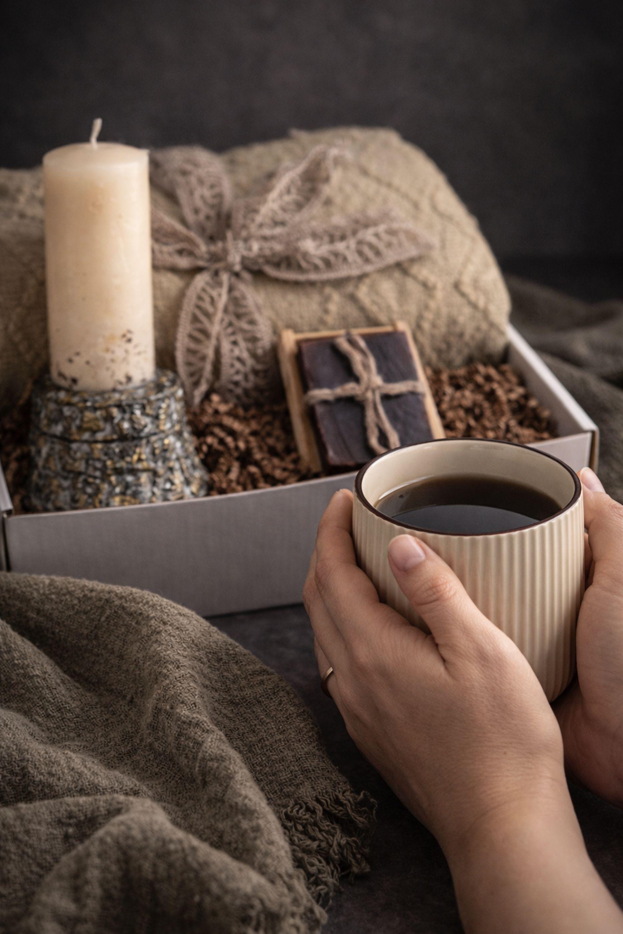 Loss of father sympathy gift box displayed on dark charcoal background with cozy olive knit blanket, handmade pillar candle with textured stone-style base and subtle gold accents, natural handmade soap on wooden holder, ceramic mug with spoon, thoughtful bereavement care package designed for condolence support, memorial gift for grieving family after dad loss, meaningful comfort present during funeral or remembrance