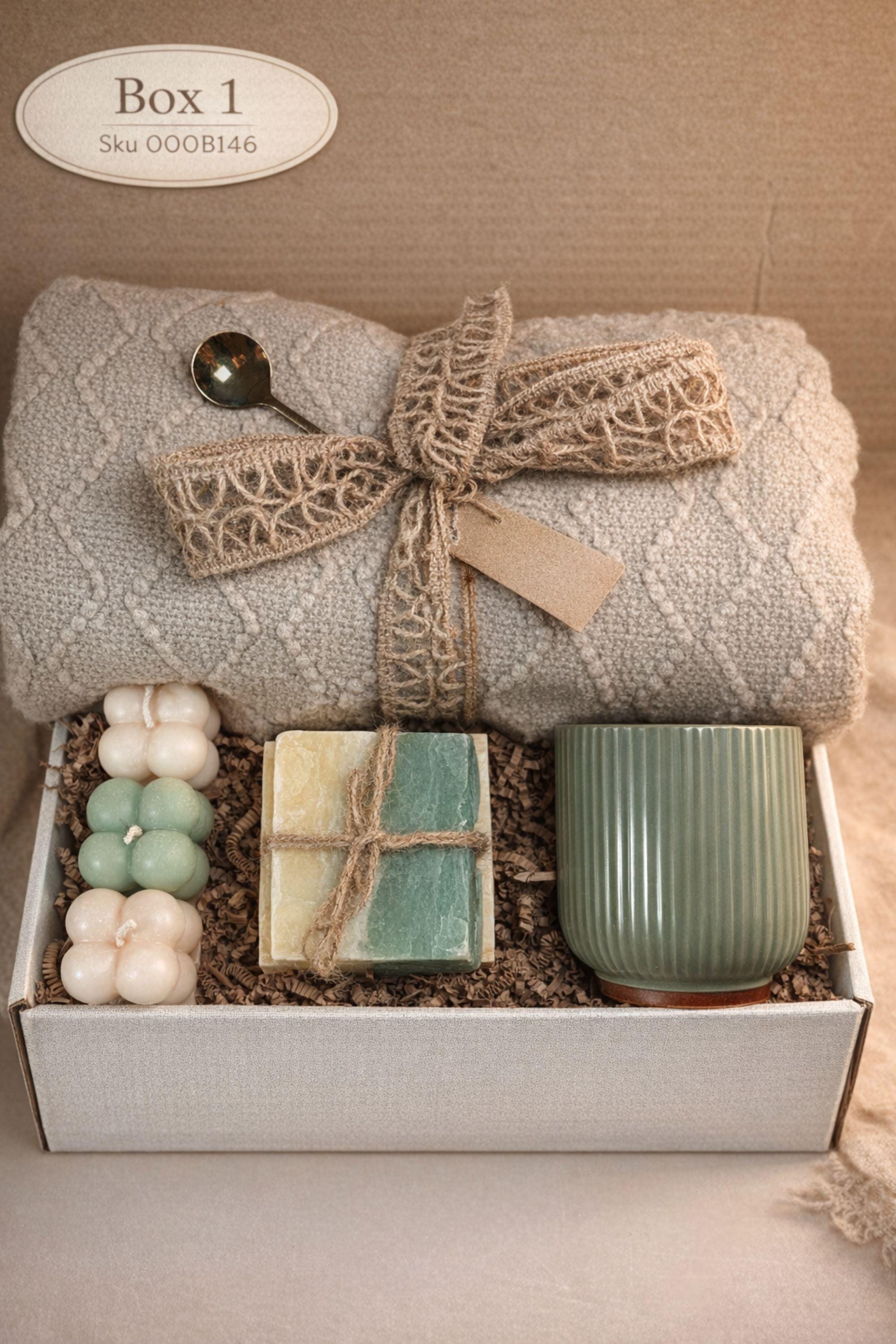 Sending You Hugs grief support gift box with sage knit blanket, ribbed green ceramic mug, handmade two-tone artisan soap, stainless steel spoon, and three bubble candles arranged inside kraft box on warm beige linen background. Sympathy care package designed for comfort during difficult times, loss support, thinking of you gift, and emotional encouragement.
