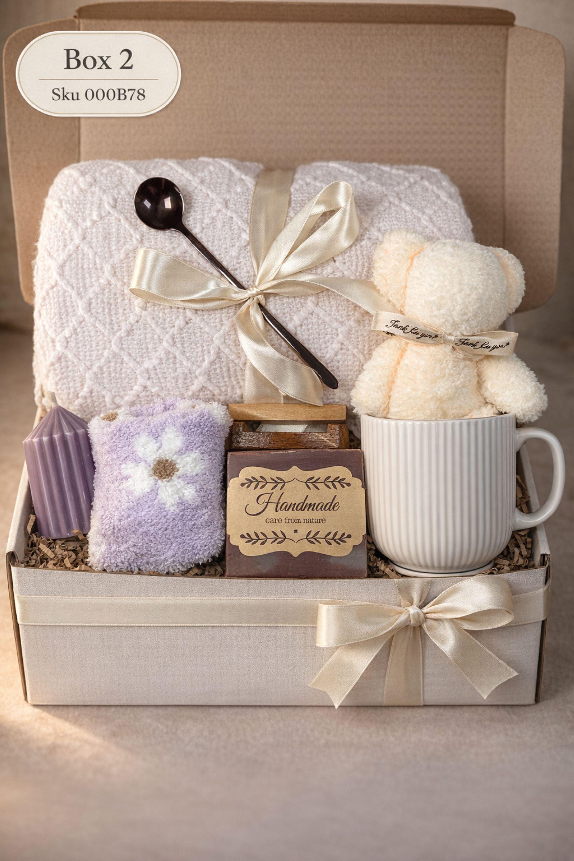 Sending You Hugs grief support gift box with sage knit blanket, ribbed green ceramic mug, handmade two-tone artisan soap, stainless steel spoon, and three bubble candles arranged inside kraft box on warm beige linen background. Sympathy care package designed for comfort during difficult times, loss support, thinking of you gift, and emotional encouragement.