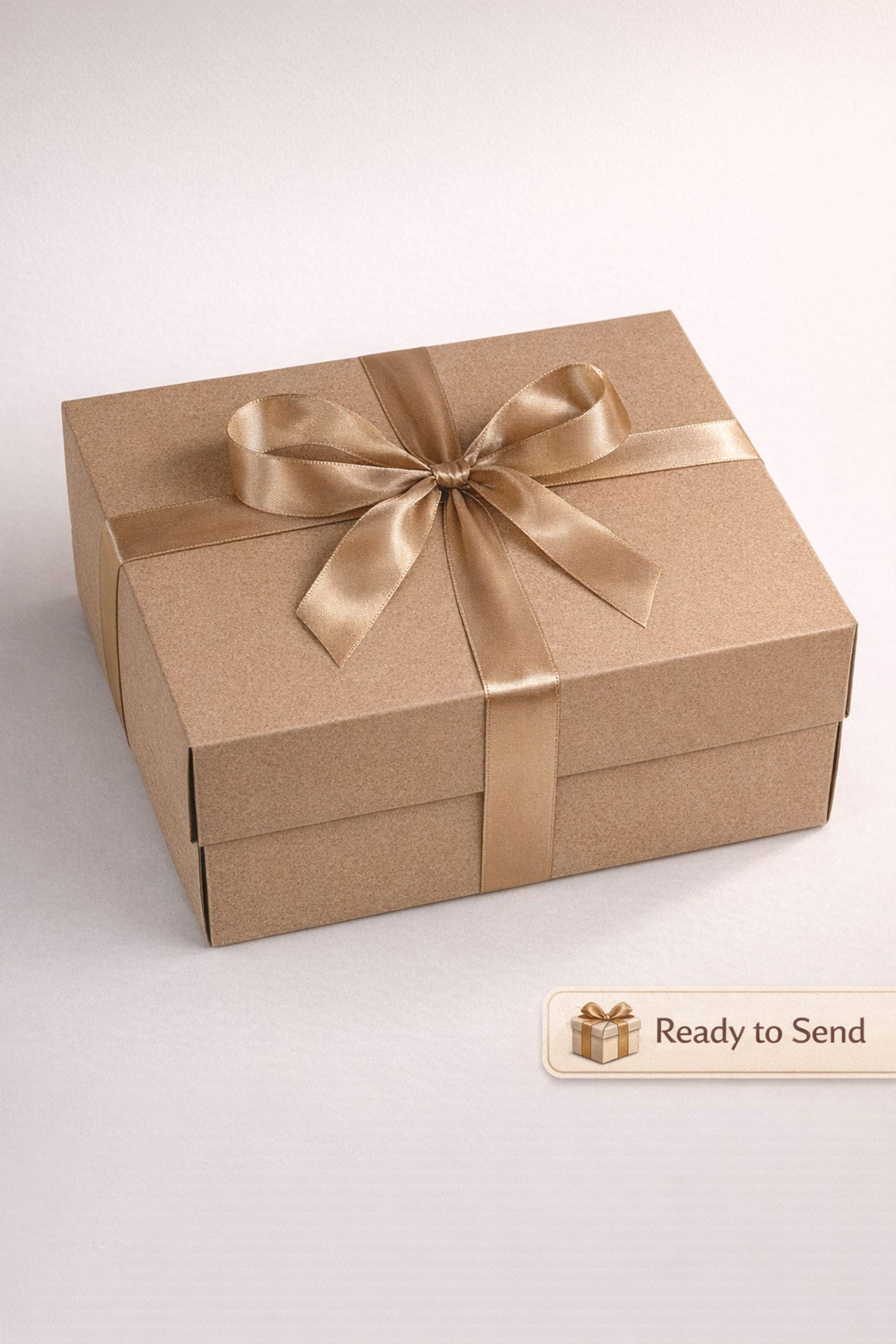 Sympathy gift box for loss of husband displayed on mouse grey linen background, open white 10x13x5 comfort care package featuring handmade 24K textured candle with stone base, cozy knit blanket tied with satin ribbon, cream ceramic mug with spoon, natural handmade soap on wooden holder, and rustic crinkle paper filler. Bereavement gift for grieving wife, condolence present, memorial comfort box, grief support package designed to send love and healing.
