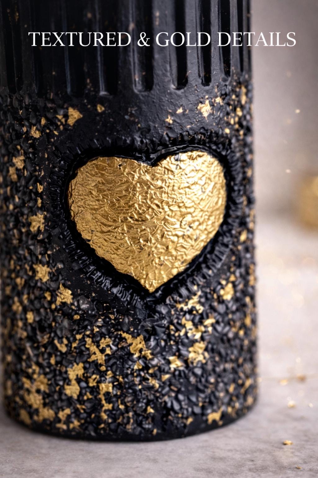Close-up of black gold sculptural candle with textured surface and gold heart detail, luxury decorative candle, modern minimalist home decor, artistic statement candle, aesthetic black and gold design