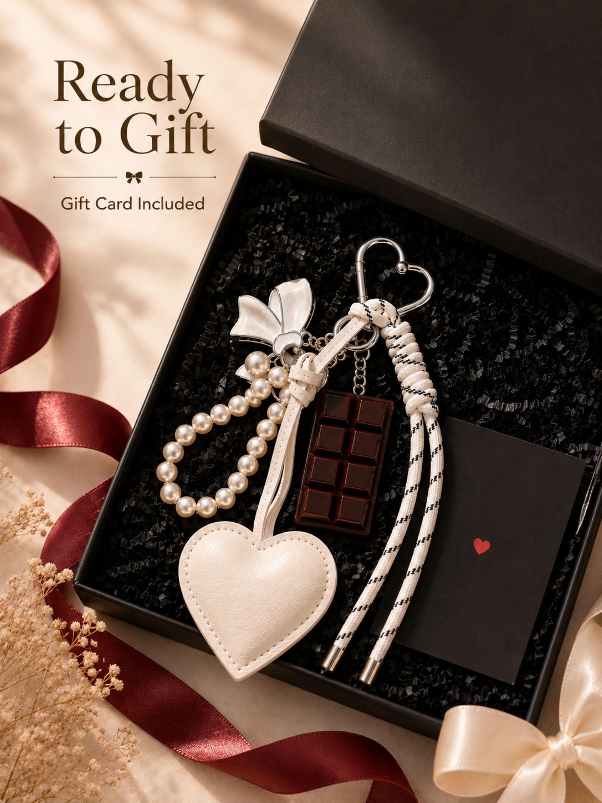 Heart bag charm featuring a white heart charm, pearl keychain loop, silver bow charm, chocolate charm and rope tassel attached to a luxury handbag. Coquette bag charm inspired by Y2K fashion, kawaii accessories and trendy purse charms. Decorative handbag accessory designed for tote bags, purses, shoulder bags, backpacks, canvas totes and beach bags. Cute statement bag charm for women and teen girls. Fashion keychain accessory perfect for everyday handbags, summer totes personalized purse styling