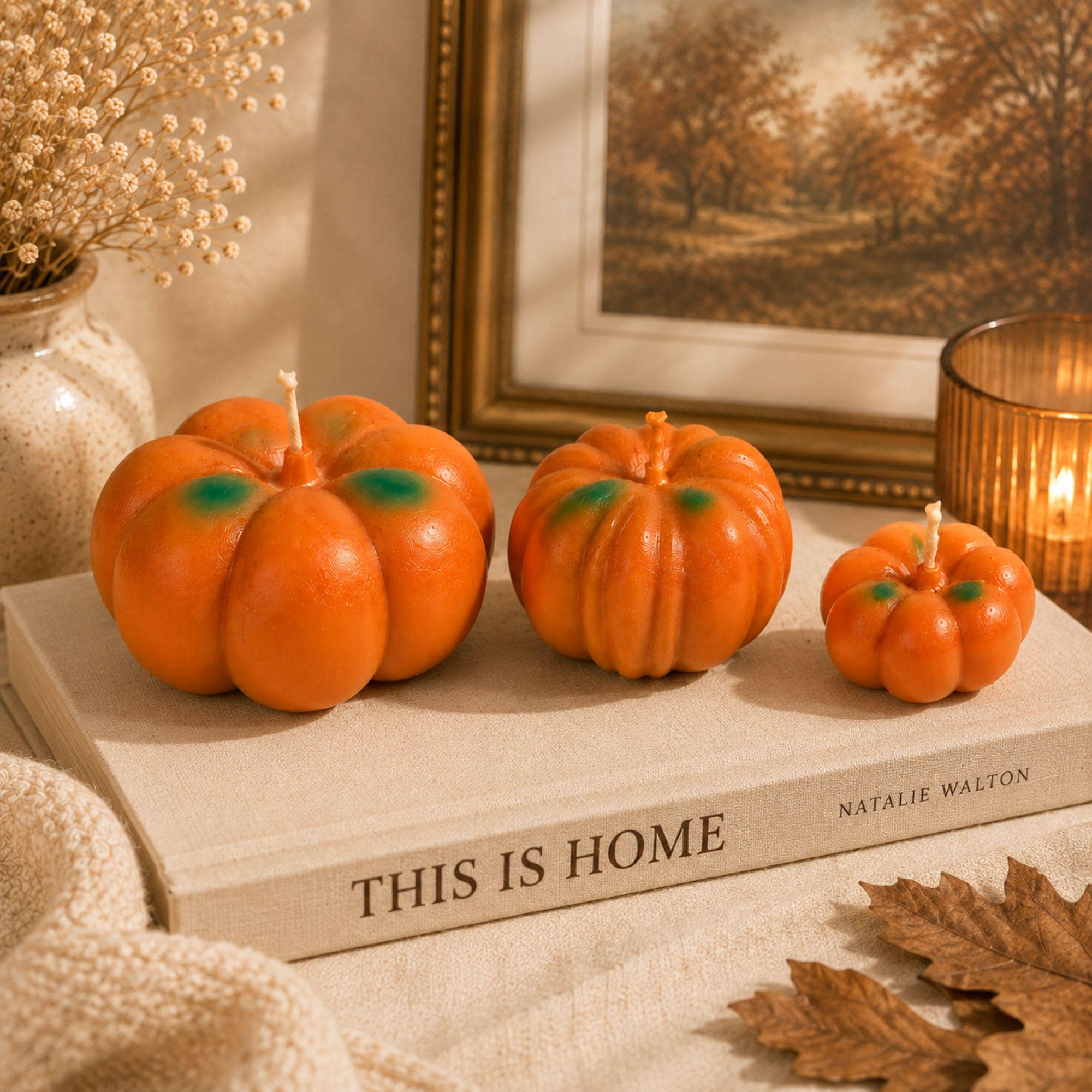 Three handmade pumpkin candles displayed together on a cozy fall mantel, featuring large, medium and small orange pumpkin shapes with green accents. Pumpkin Pie scented candle trio creates warm autumn home decor for fireplace styling, Thanksgiving decorations, seasonal displays and fall entertaining. Decorative pumpkin candle set adds handcrafted harvest character to a mantel, console table or entryway.