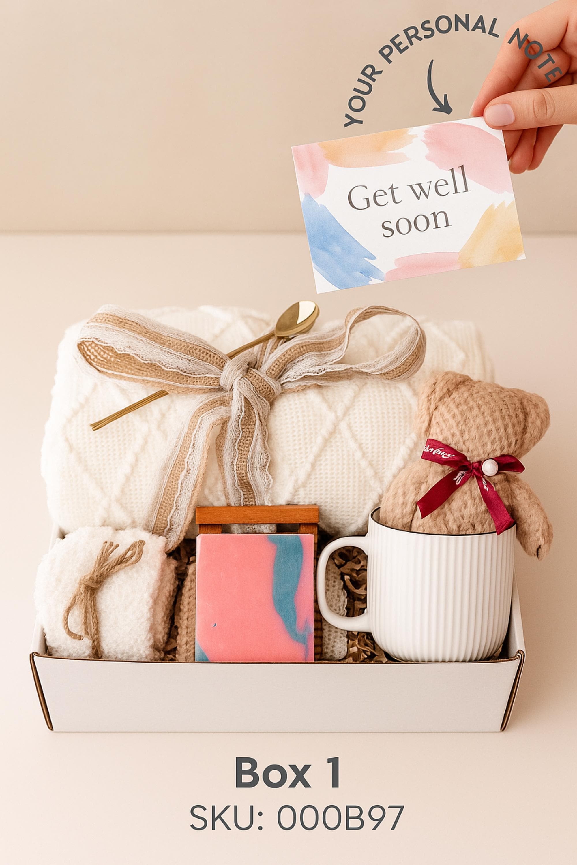 Winter self-care gift box featuring a cozy white blanket with ribbon, a teddy-bear-shaped washcloth, handmade pink and blue soap on a wooden tray, and a soft crocheted bear sitting in a white mug. Displayed on a rustic wood surface with snowy accents, this cozy winter spa set makes a thoughtful holiday comfort gift, pamper box, relaxation present, or get-well care package for women.