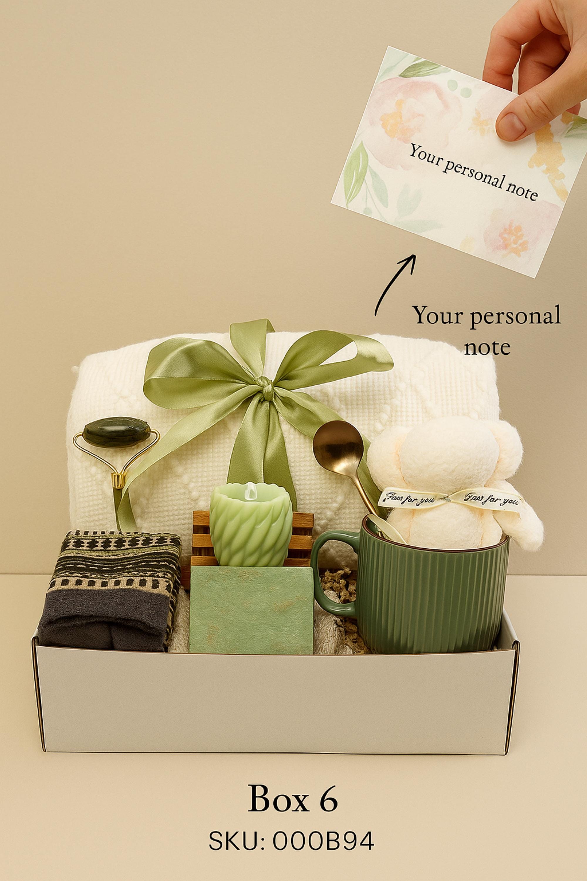 Winter self-care gift box featuring a cozy white blanket with ribbon, a teddy-bear-shaped washcloth, handmade pink and blue soap on a wooden tray, and a soft crocheted bear sitting in a white mug. Displayed on a rustic wood surface with snowy accents, this cozy winter spa set makes a thoughtful holiday comfort gift, pamper box, relaxation present, or get-well care package for women.