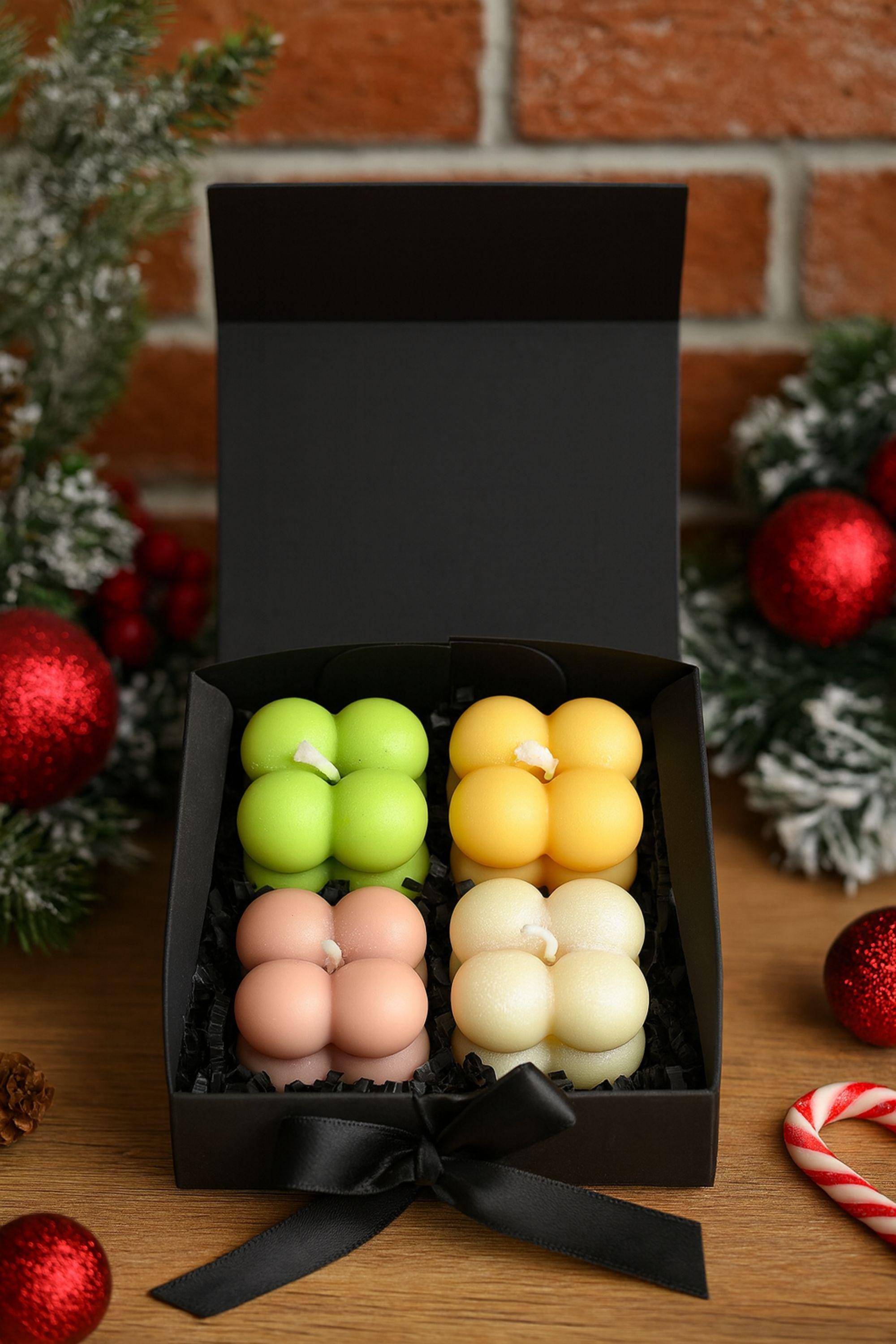Christmas spa gift scene with bubble candle gift box, pine branches and red ornaments. Holiday candle gift for her, stocking stuffer and Secret Santa present.