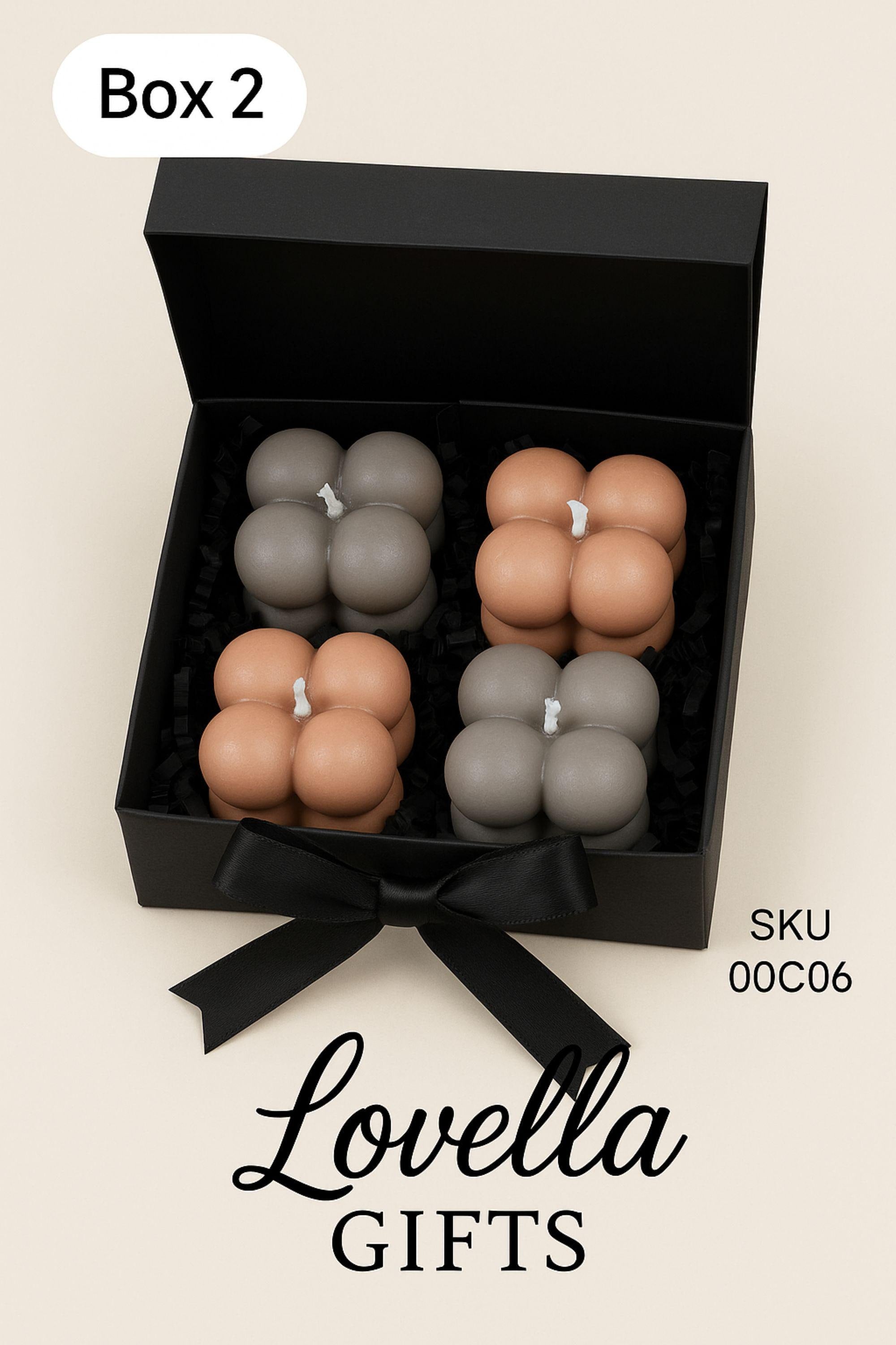 Christmas bubble candle gift box with four pastel mini bubble candles in a black box with ribbon, styled with festive greenery and ornaments. Cozy holiday spa gift set and small Christmas present for her.