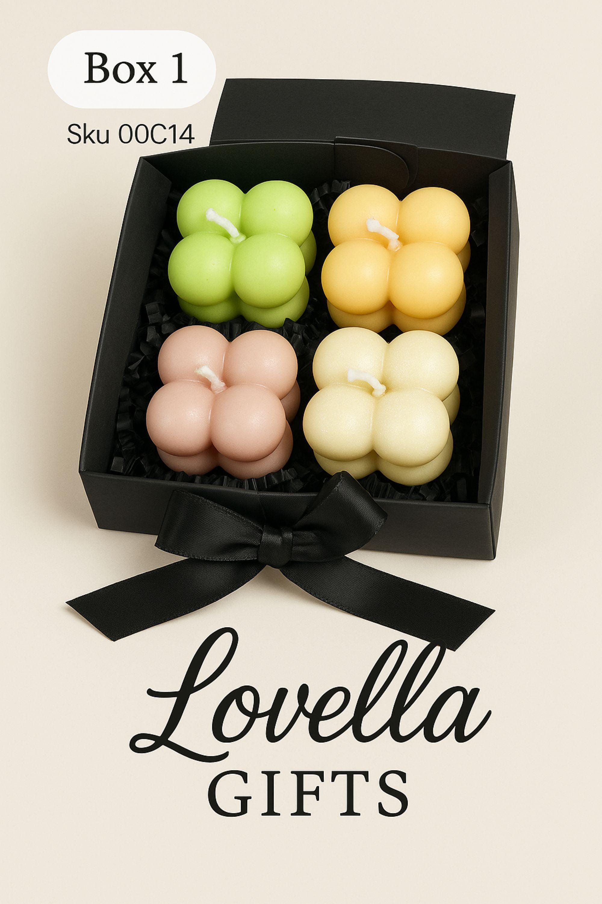 Christmas bubble candle gift box with four pastel mini bubble candles in a black box with ribbon, styled with festive greenery and ornaments. Cozy holiday spa gift set and small Christmas present for her.