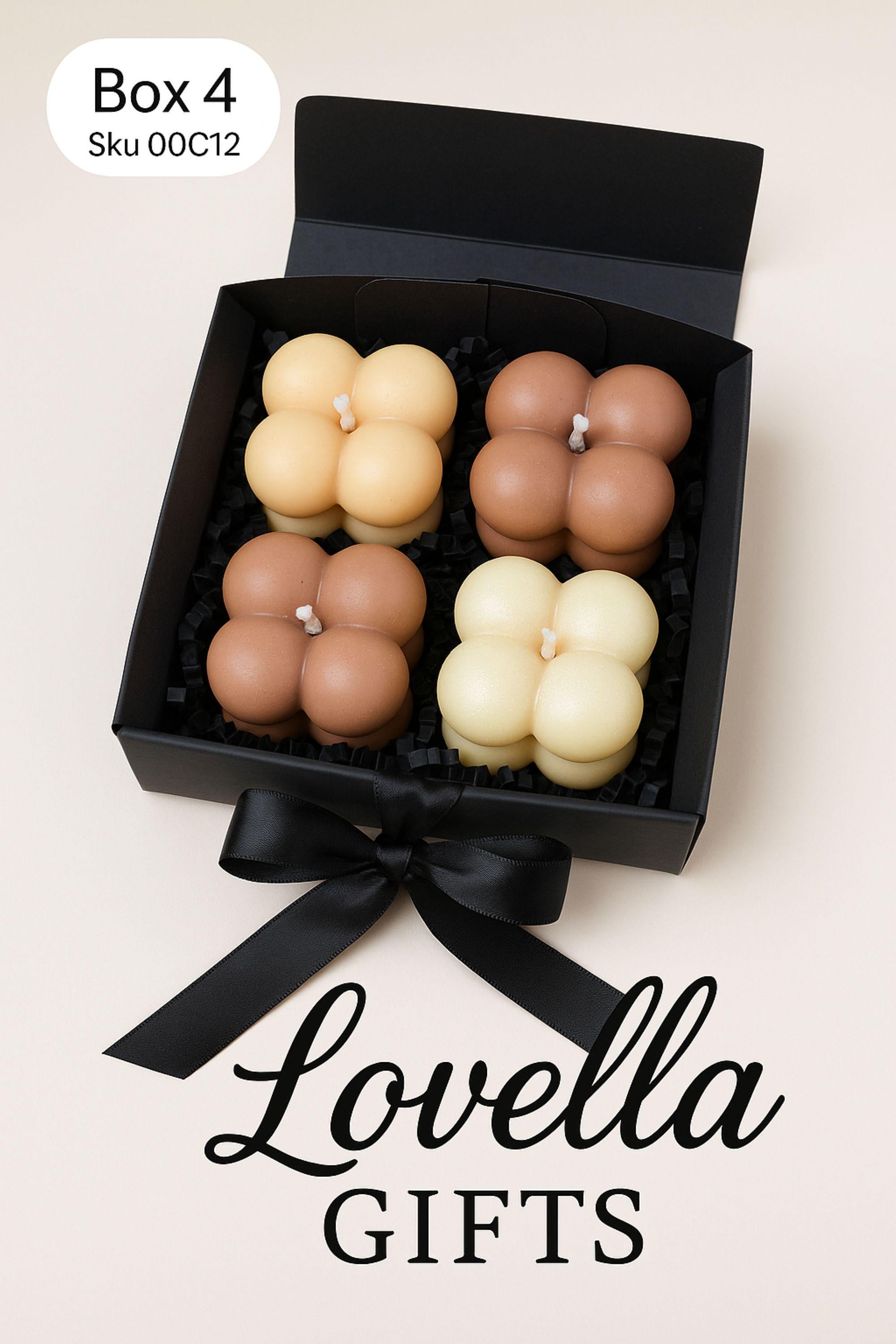 Christmas bubble candle gift box with four pastel mini bubble candles in a black box with ribbon, styled with festive greenery and ornaments. Cozy holiday spa gift set and small Christmas present for her.