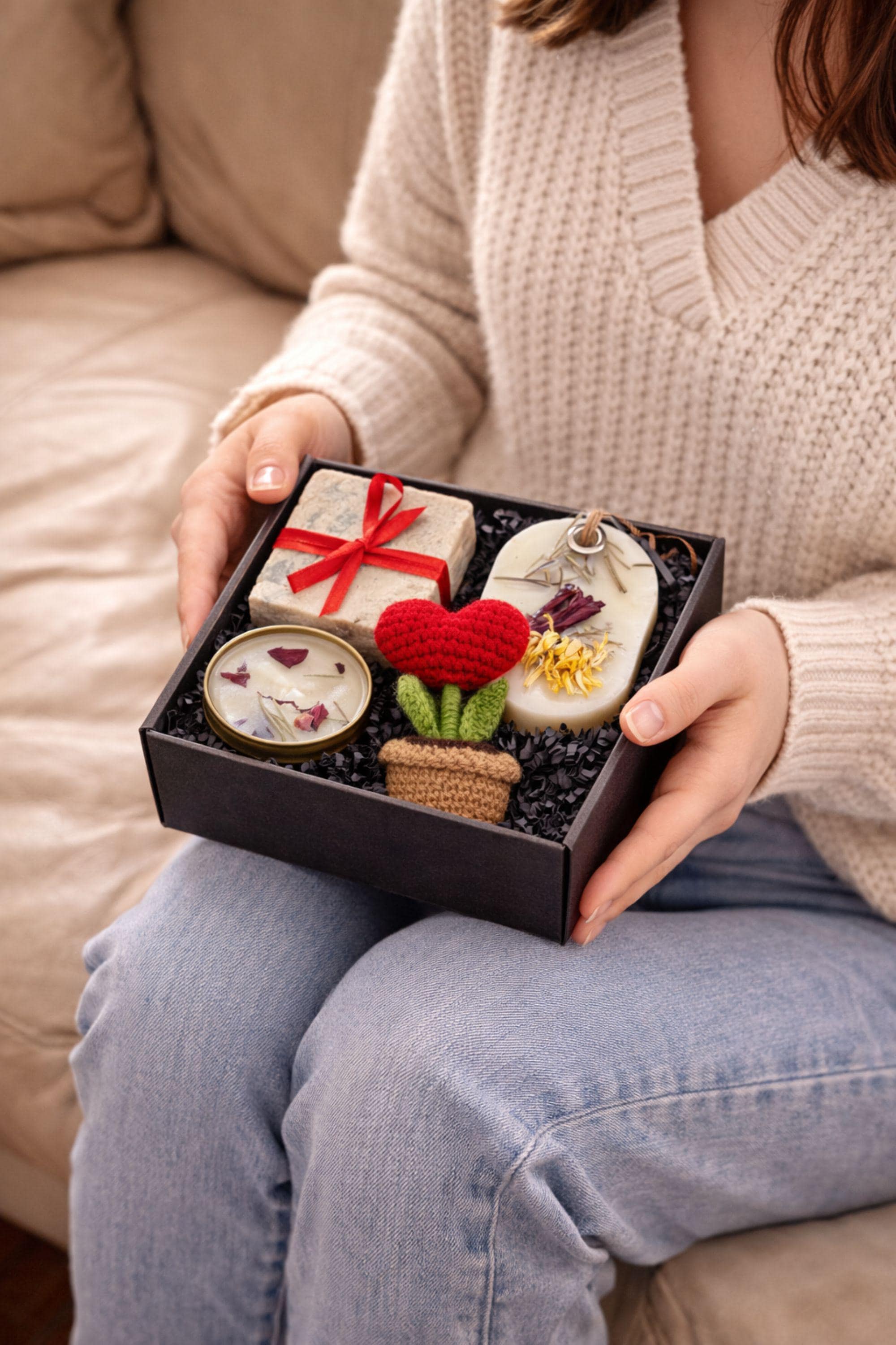 Thinking of you gift box with handmade soap tied with red ribbon, botanical candle in metal tin, wax sachet with dried flowers and crochet flower arranged inside a black gift box. Cozy comfort handmade gift for her, just because care package, small meaningful present for long distance support, encouragement, sympathy or thoughtful gesture. Gift ready handmade box designed to show care, warmth and attention.