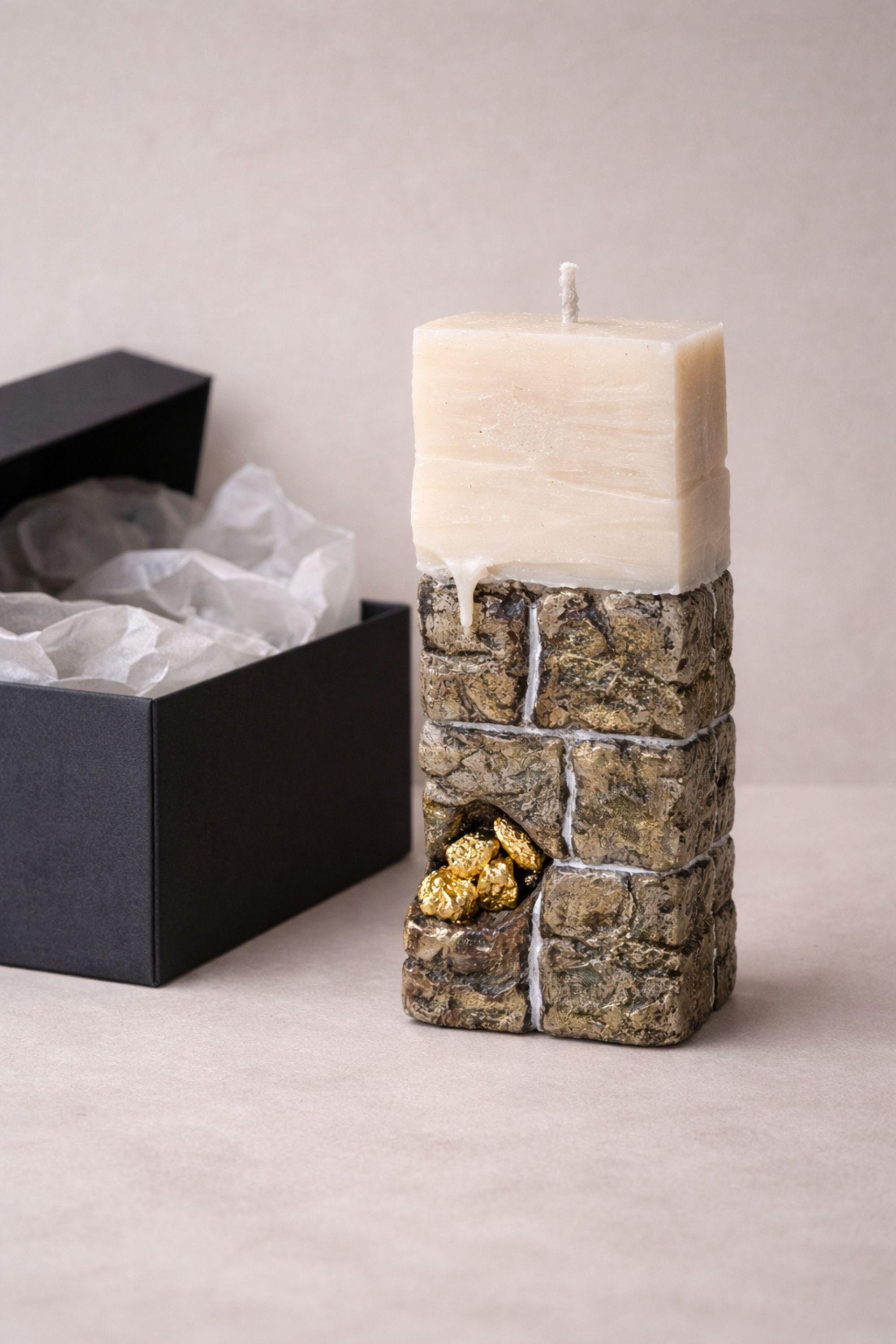 Luxury sculptural candle gift featuring a stone-inspired texture and gold detail, showcased in elegant packaging.