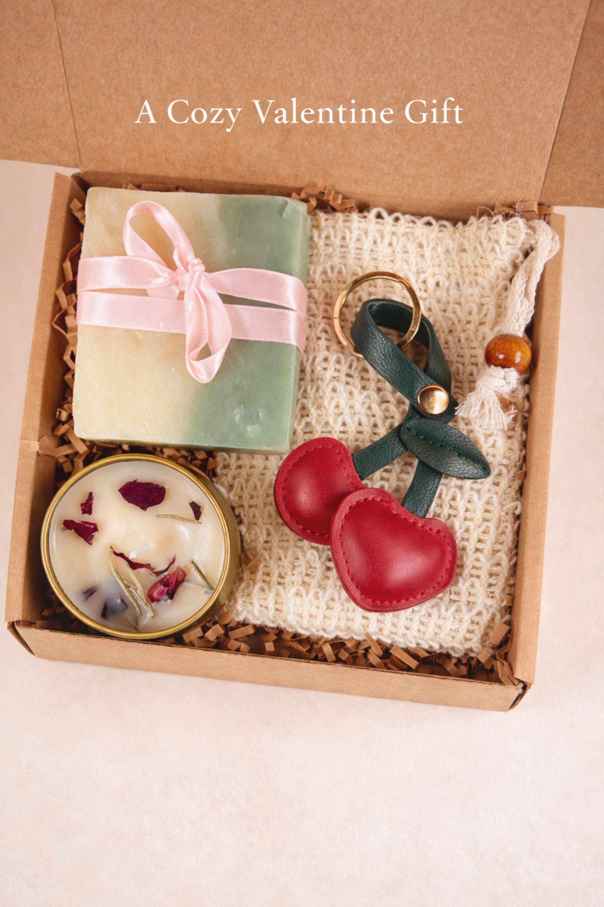 Valentine’s Day thinking of you gift box with handmade soap, botanical candle, crochet washcloth, and leather cherry keychain arranged in a kraft gift box. Cozy Valentine care package featuring artisan soap tied with ribbon, floral candle in tin, soft eco washcloth, and charming heart-inspired cherry accessory. Meaningful Valentine gift for her, long distance Valentine care package, or romantic handmade Valentine present ready to gift.