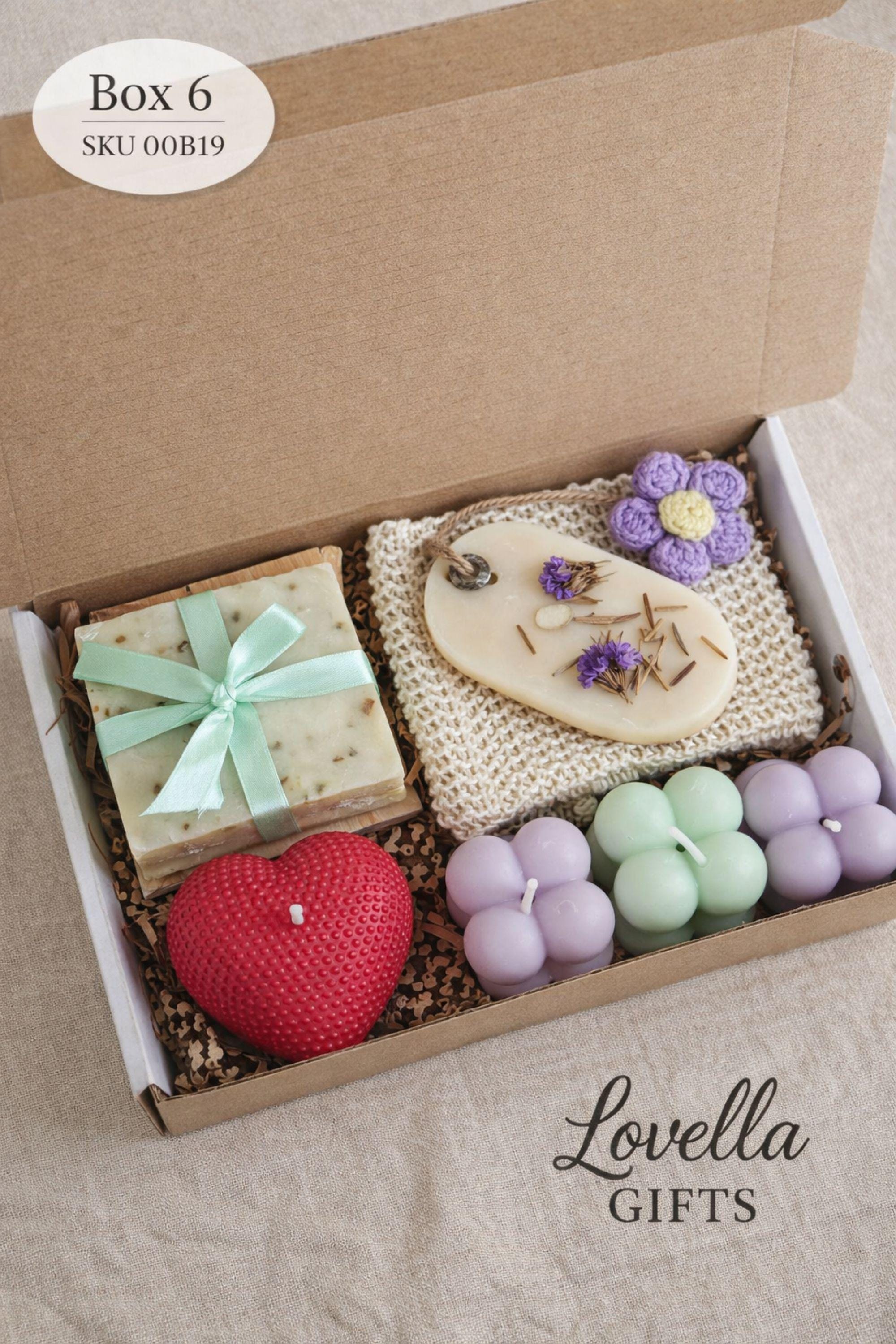 Thinking of you gift box with handmade heart candle, cozy knitted socks, bath salt tubes tied with red ribbon, soft cotton washcloth, and leather heart keychain arranged inside a kraft gift box. Small meaningful comfort gift designed as a care package for her, perfect for sending love, warmth, and support during long distance moments, stressful times, or just because. Handmade cozy gift set ready to give.