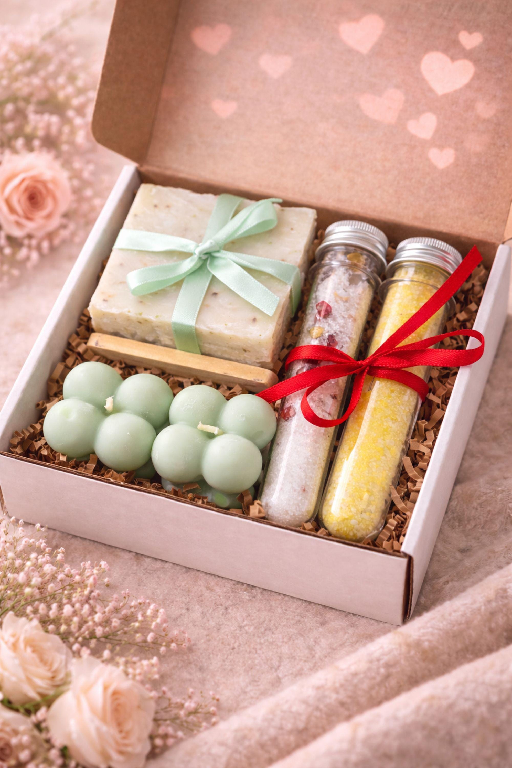 Valentine gift box for her displayed open in a kraft box, featuring handmade sage bubble candles, natural soap tied with a soft ribbon, and two glass tubes of bath salts arranged neatly with filler. Calm Valentine care package designed in soothing green and neutral tones, perfect as a gentle handmade Valentine gift, comfort box, or thoughtful alternative to traditional romantic presents.
