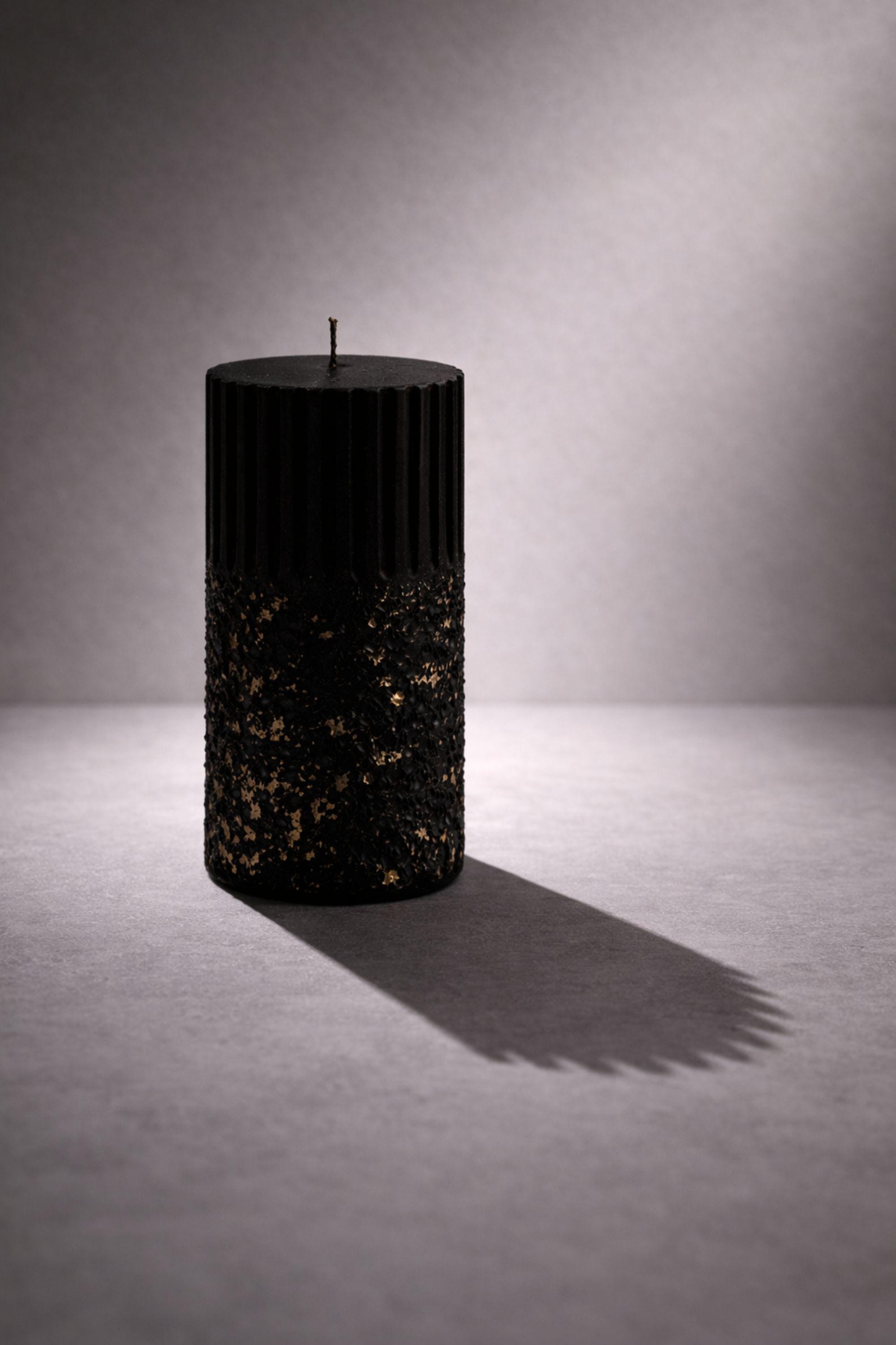 Single black sculptural wax object photographed in a calm, minimal composition to study silhouette, texture, and vertical rhythm. The ribbed structure and textured surface reinforce AuraBox’s form-focused design language.