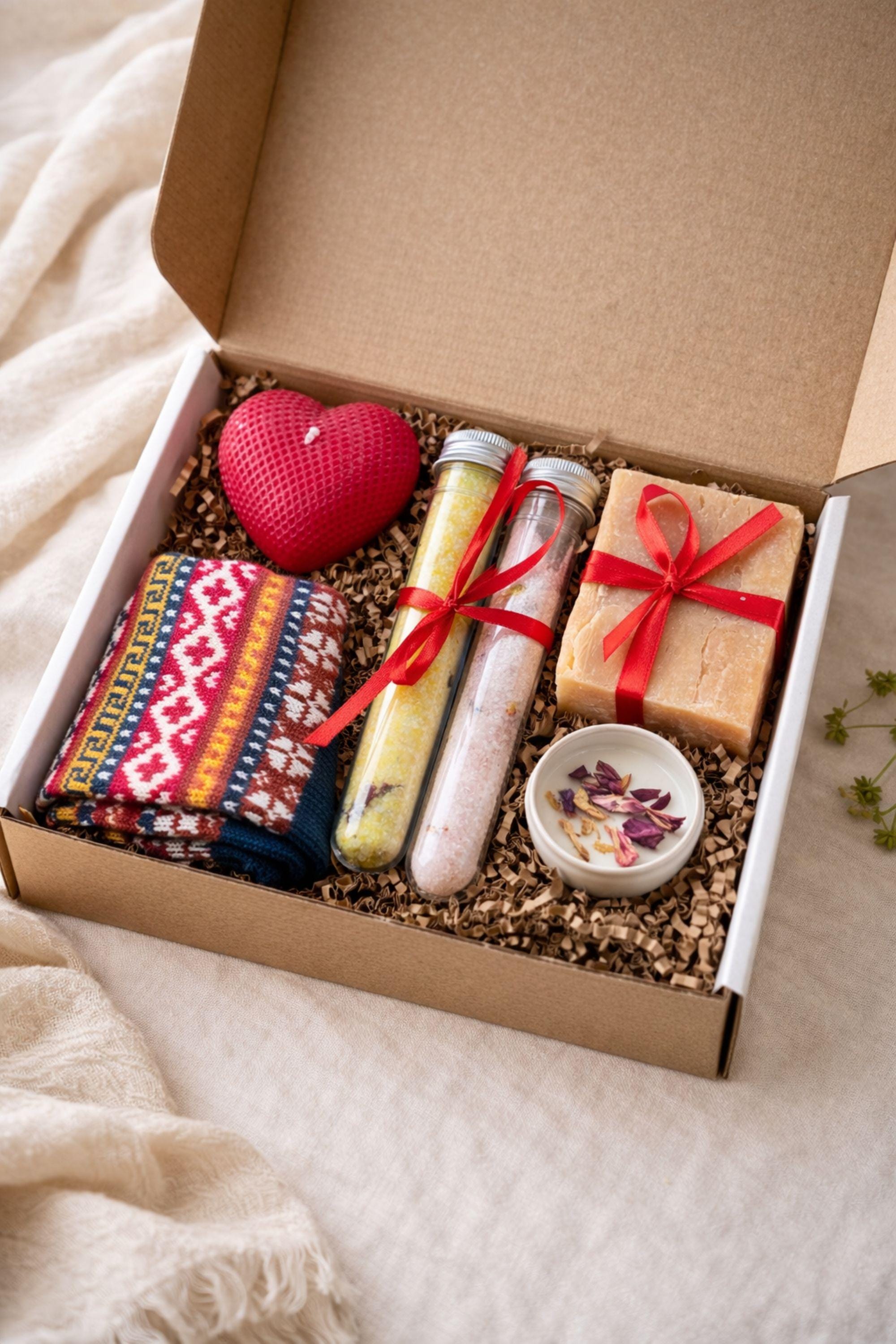 Cozy Valentine gift box with handmade soap tied with red ribbon, heart shaped candle, scented candle with dried flowers, bath salts in glass tubes, and knitted washcloth arranged in kraft gift box. Romantic self care gift for her, comfort care package, handmade Valentine’s Day gift, thinking of you box, ready to gift cozy relaxation set.