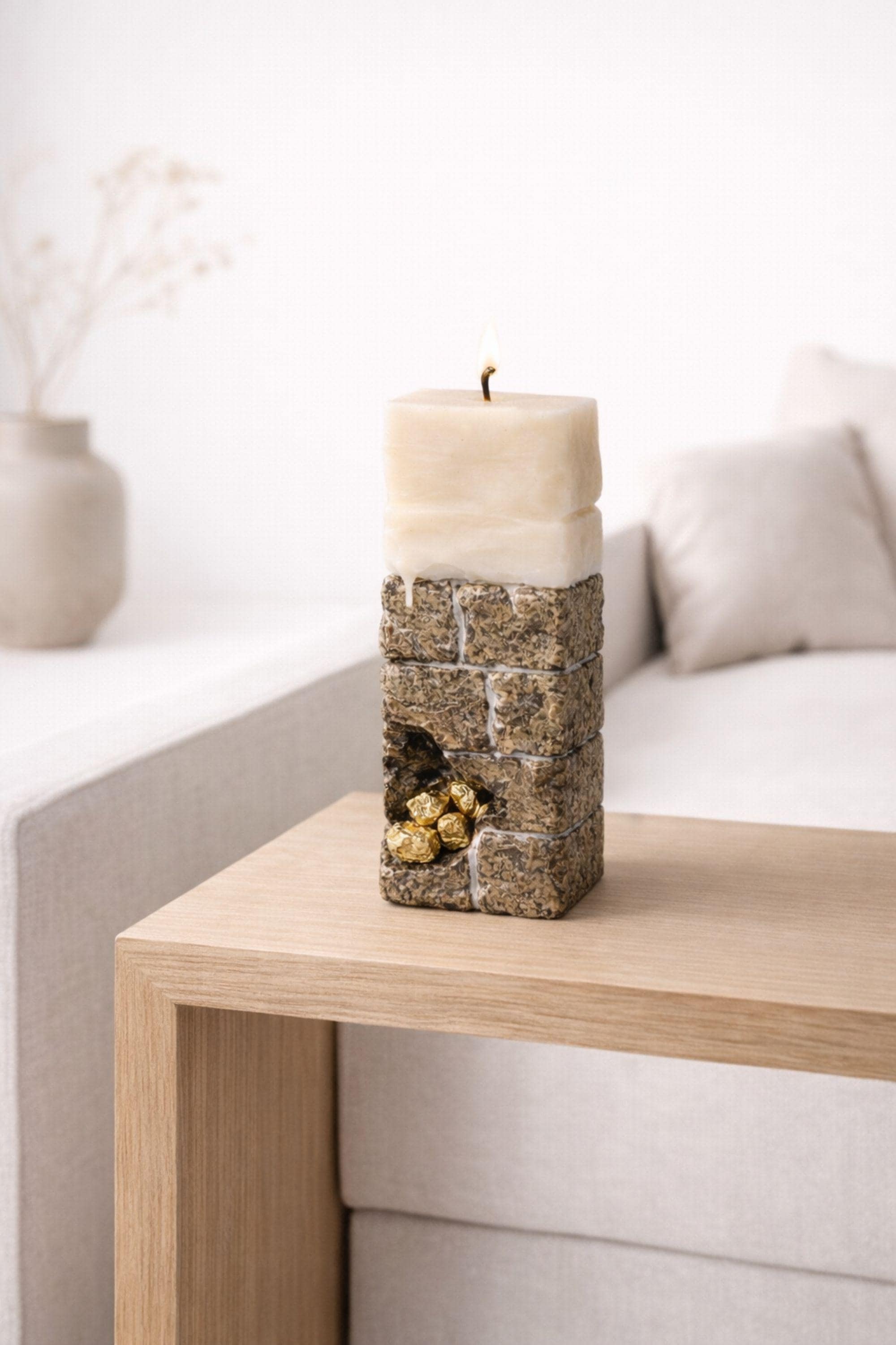 Minimalist sculptural candle decor on a wooden table in a modern living room setting.