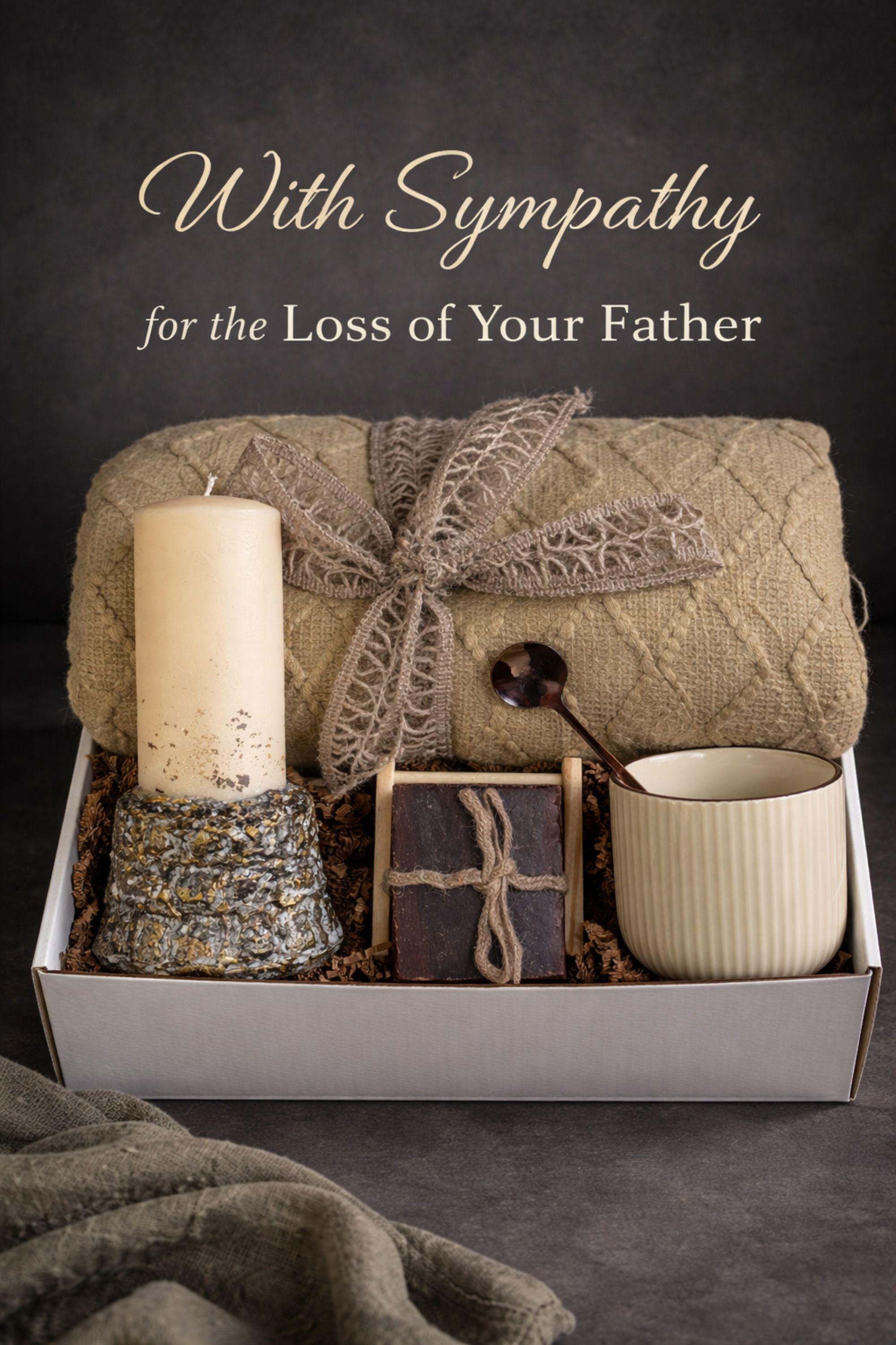 Loss of father sympathy gift box displayed on dark charcoal background with cozy olive knit blanket, handmade pillar candle with textured stone-style base and subtle gold accents, natural handmade soap on wooden holder, ceramic mug with spoon, thoughtful bereavement care package designed for condolence support, memorial gift for grieving family after dad loss, meaningful comfort present during funeral or remembrance