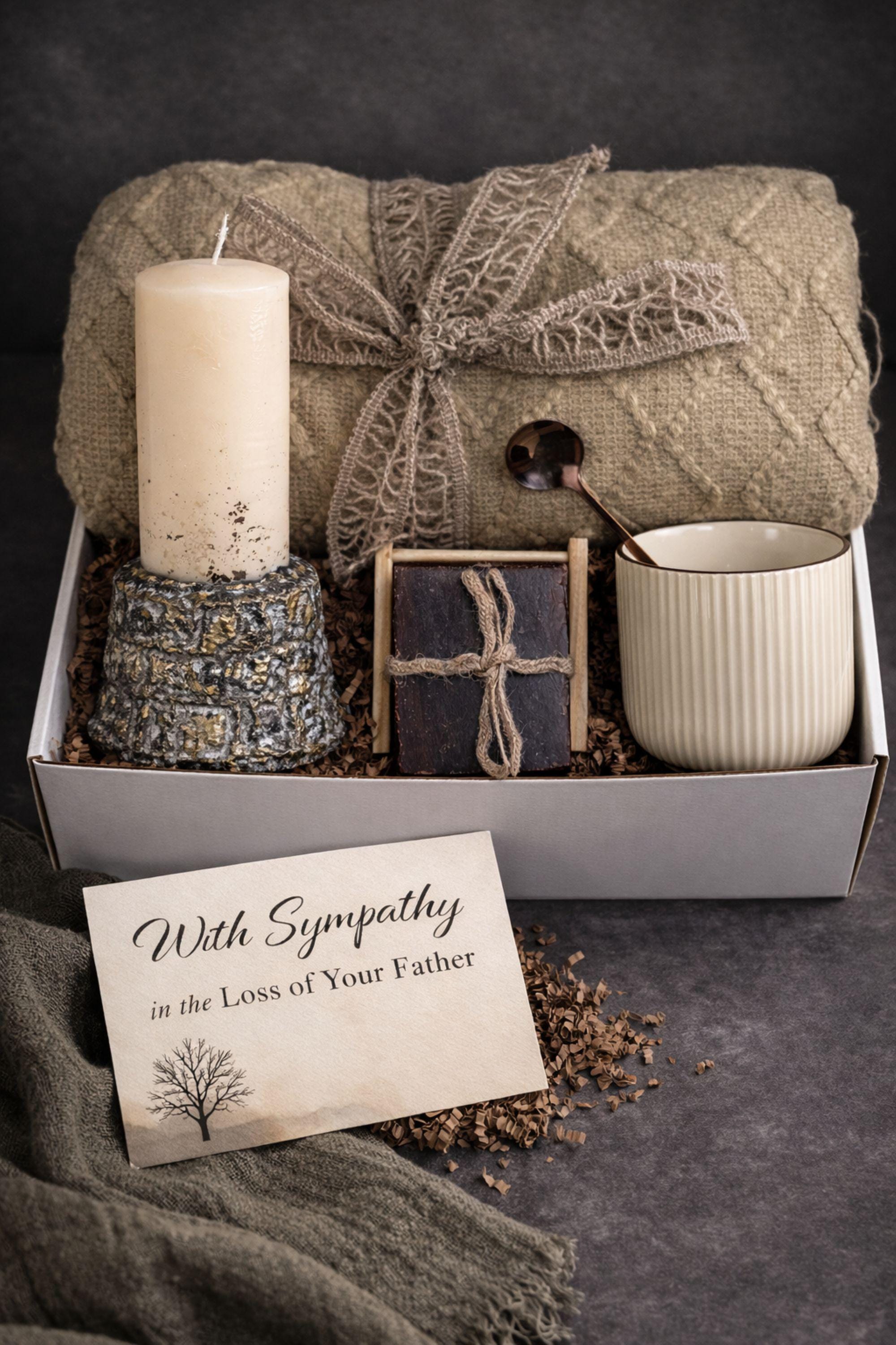 Loss of father sympathy gift box displayed on dark charcoal background with cozy olive knit blanket, handmade pillar candle with textured stone-style base and subtle gold accents, natural handmade soap on wooden holder, ceramic mug with spoon, thoughtful bereavement care package designed for condolence support, memorial gift for grieving family after dad loss, meaningful comfort present during funeral or remembrance