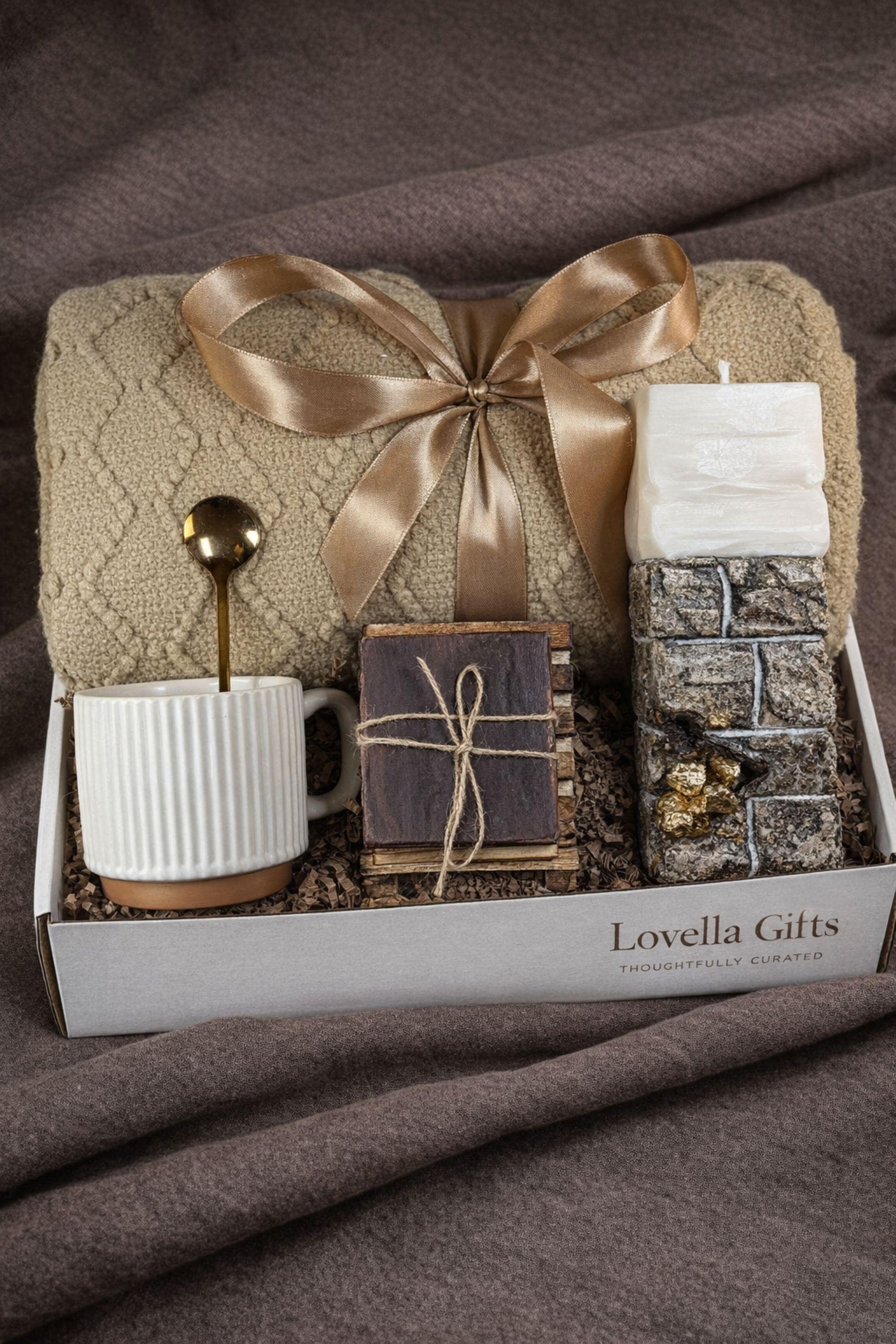 Sympathy gift box for loss of husband displayed on mouse grey linen background, open white 10x13x5 comfort care package featuring handmade 24K textured candle with stone base, cozy knit blanket tied with satin ribbon, cream ceramic mug with spoon, natural handmade soap on wooden holder, and rustic crinkle paper filler. Bereavement gift for grieving wife, condolence present, memorial comfort box, grief support package designed to send love and healing.