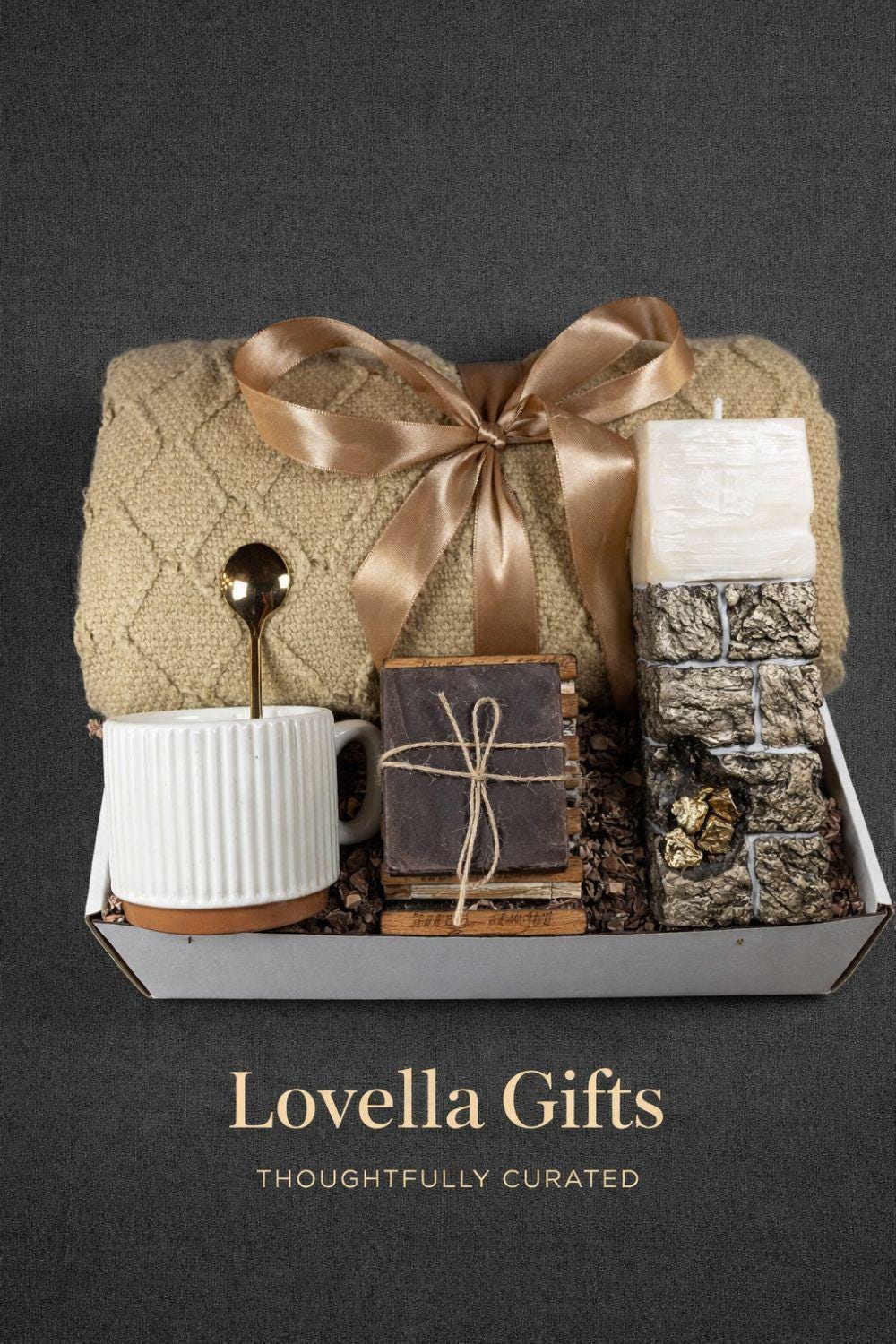 Open white sympathy gift box for loss of wife displayed on neutral mouse grey linen background, featuring soft beige knit blanket tied with satin ribbon, handcrafted 24K textured memorial candle with gold accents, ribbed ceramic mug with spoon, artisan soap on wooden stand, arranged as a thoughtful bereavement care package for grieving husband. Elegant comfort gift for widower, condolence gift box, memorial support present.
