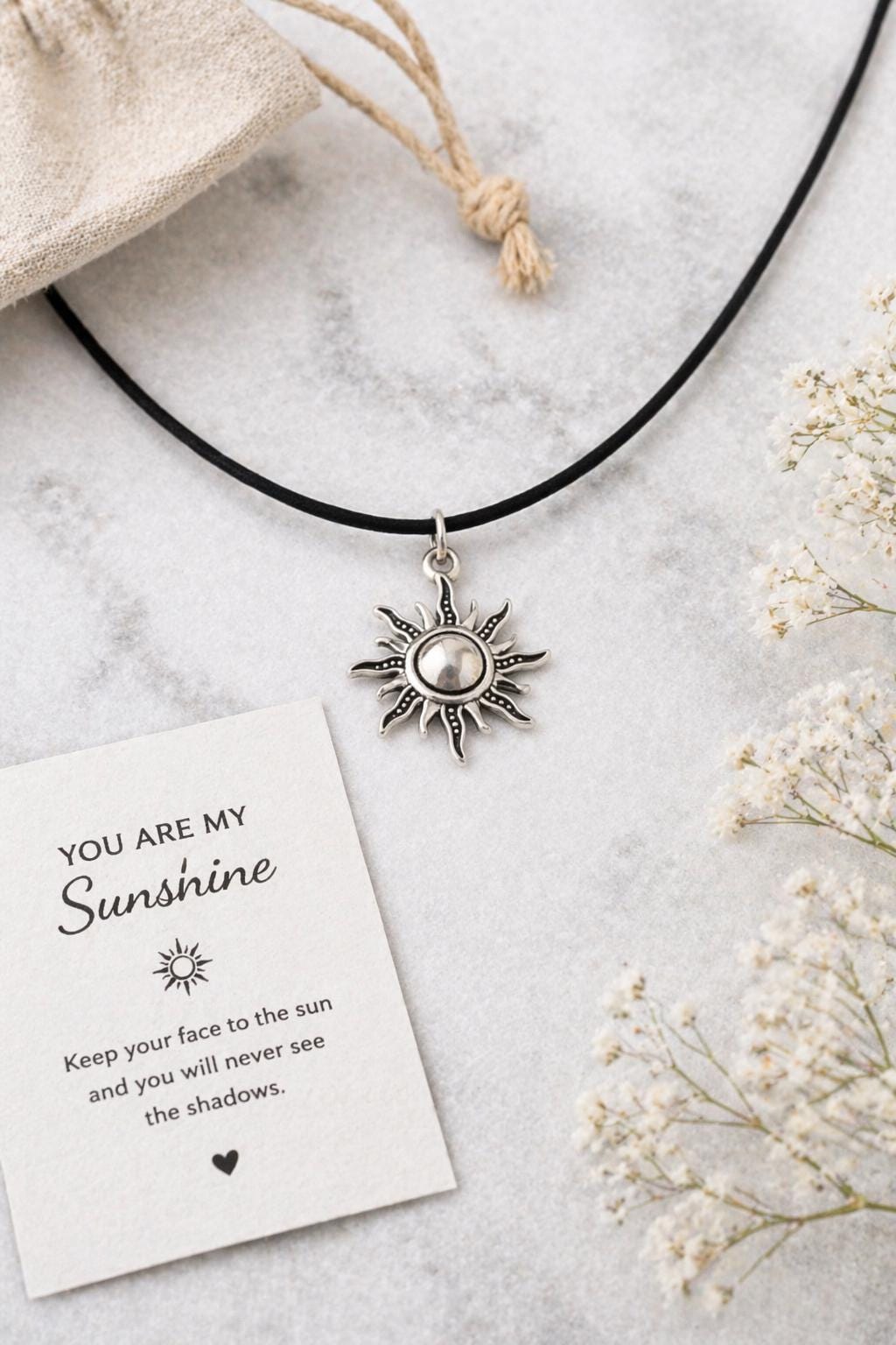 silver sun pendant necklace flat lay with flowers and card you are my sunshine celestial jewelry minimalist sun charm choker gift for her aesthetic scene