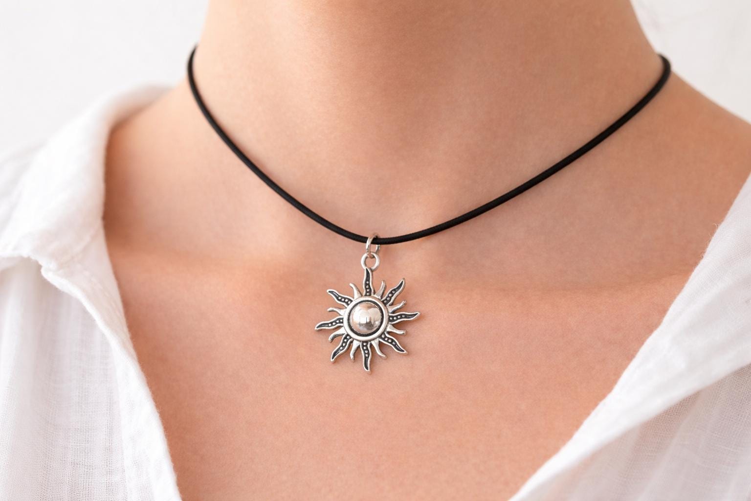 silver sun pendant necklace on woman neck minimalist celestial jewelry black cord choker clean background gift for her y2k style sun charm necklace