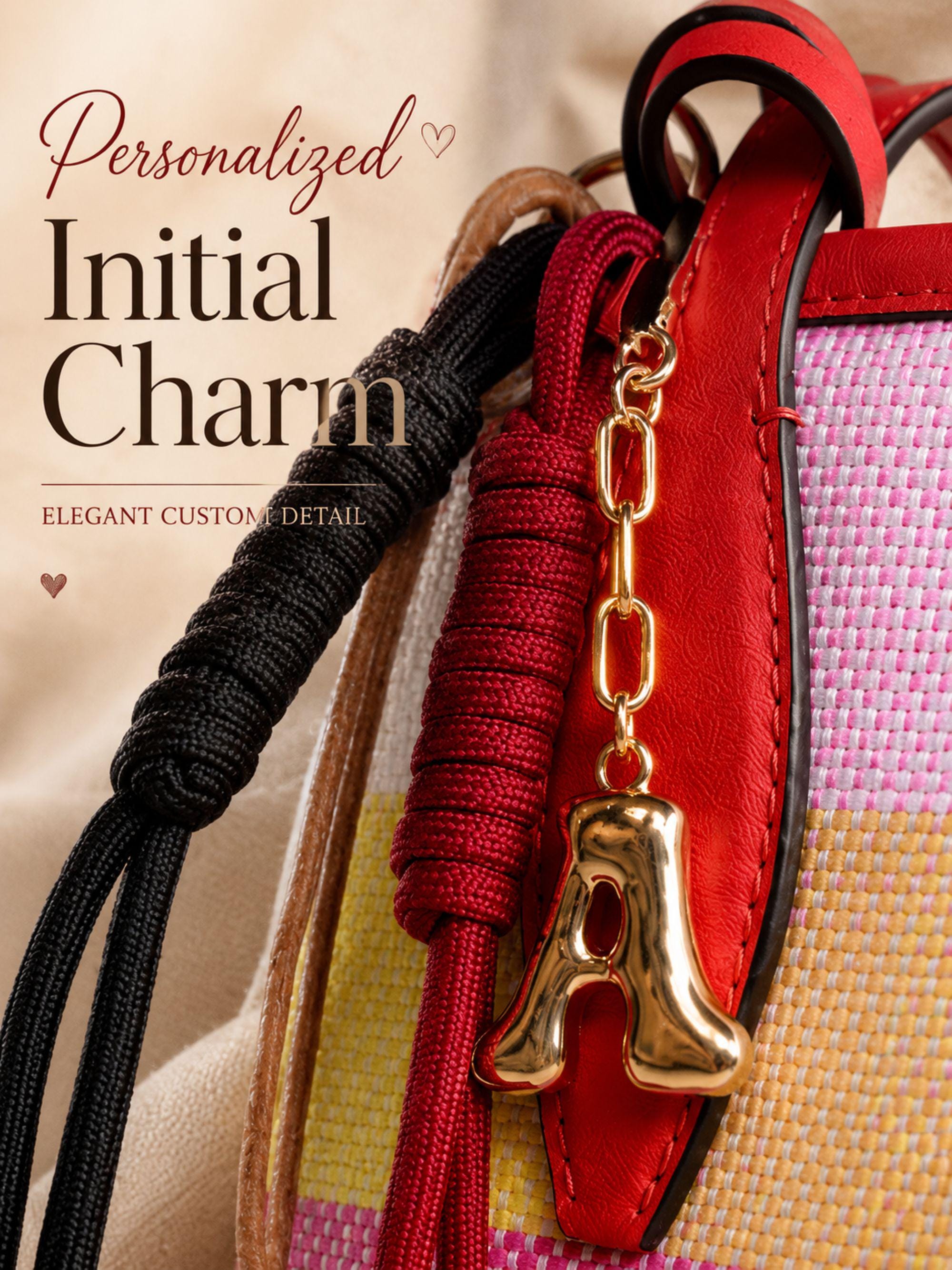 Personalized initial bag charm attached to colorful luxury tote bag with red leather trim, featuring handcrafted tassel cords, gold letter charm, artisan leather fruit accessory and boutique handbag styling. Luxury purse charm accessory for women, colorful handbag keychain, trendy tote bag decor, designer inspired purse accessory, custom initial charm gift for her, summer bag accessory, cute handbag charm, stylish purse keychain.