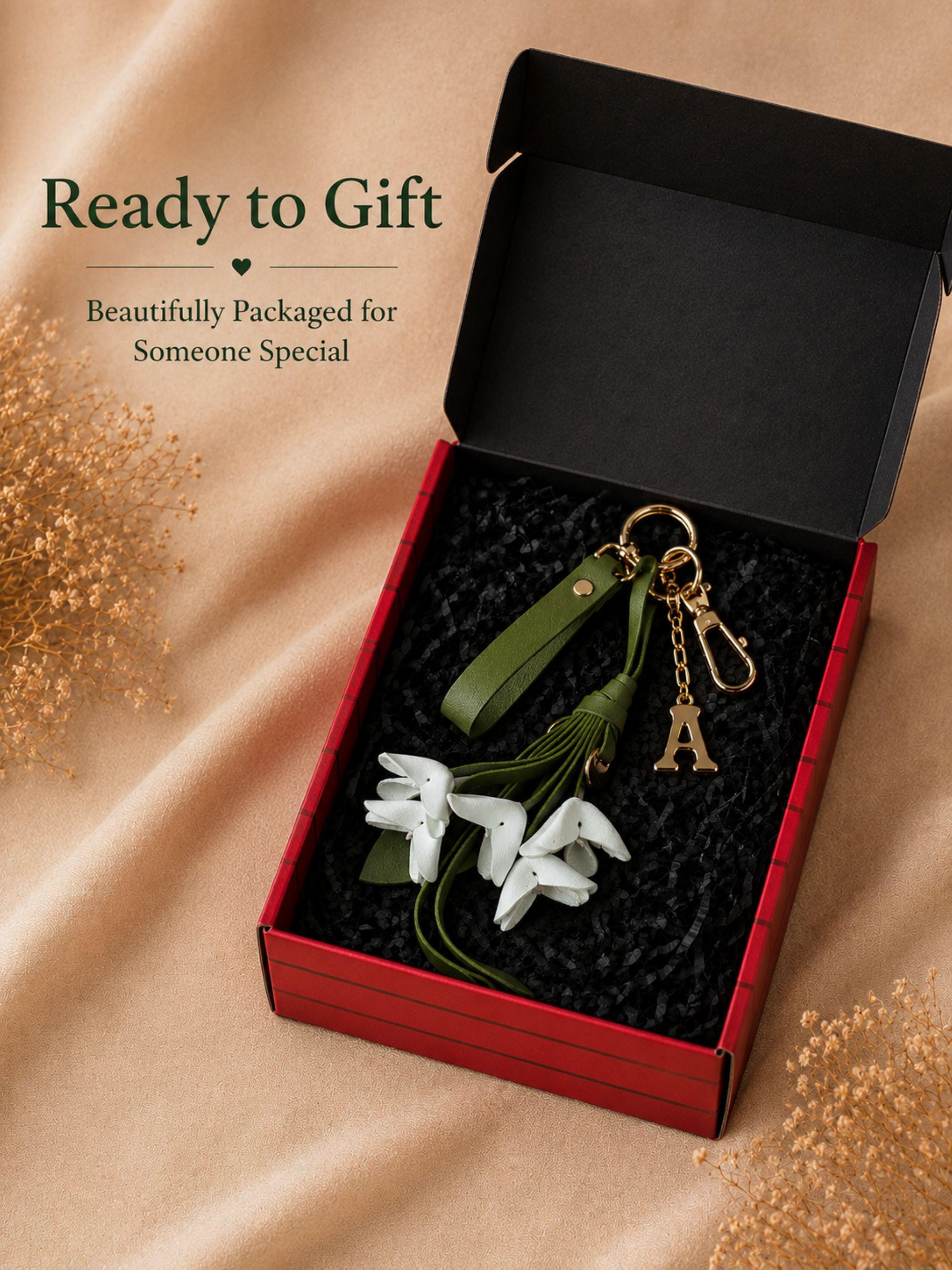 Personalized floral bag charm with initial letter charm attached to handbag featuring folded leather flowers, olive green leather tassel, gold hardware, feminine purse accessory, custom handbag charm, trendy floral keychain, gift ready purse charm, cute girly bag accessory, luxury handbag keychain for women, soft feminine fashion accessory, elegant purse charm, personalized flower keychain, boutique style bag charm, Pinterest inspired handbag accessory
