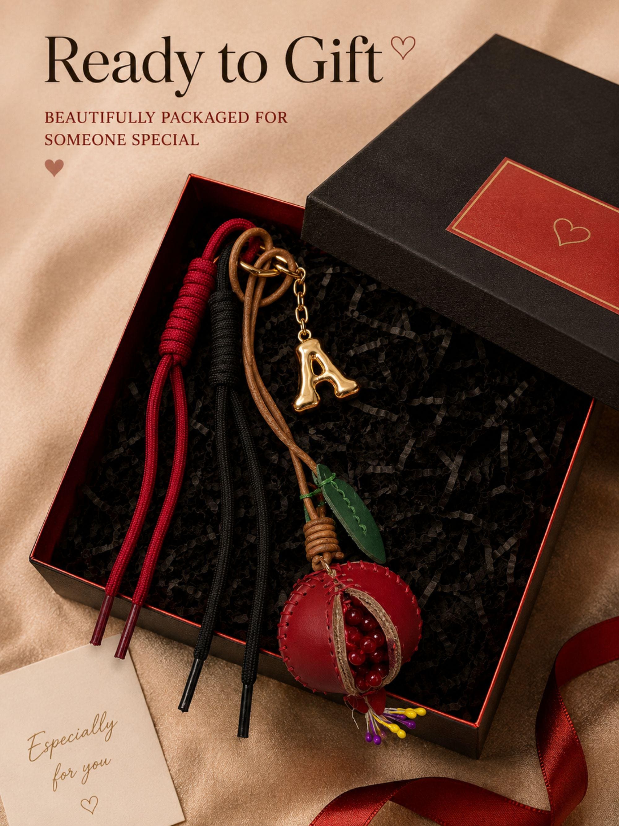 Personalized initial bag charm attached to colorful luxury tote bag with red leather trim, featuring handcrafted tassel cords, gold letter charm, artisan leather fruit accessory and boutique handbag styling. Luxury purse charm accessory for women, colorful handbag keychain, trendy tote bag decor, designer inspired purse accessory, custom initial charm gift for her, summer bag accessory, cute handbag charm, stylish purse keychain.