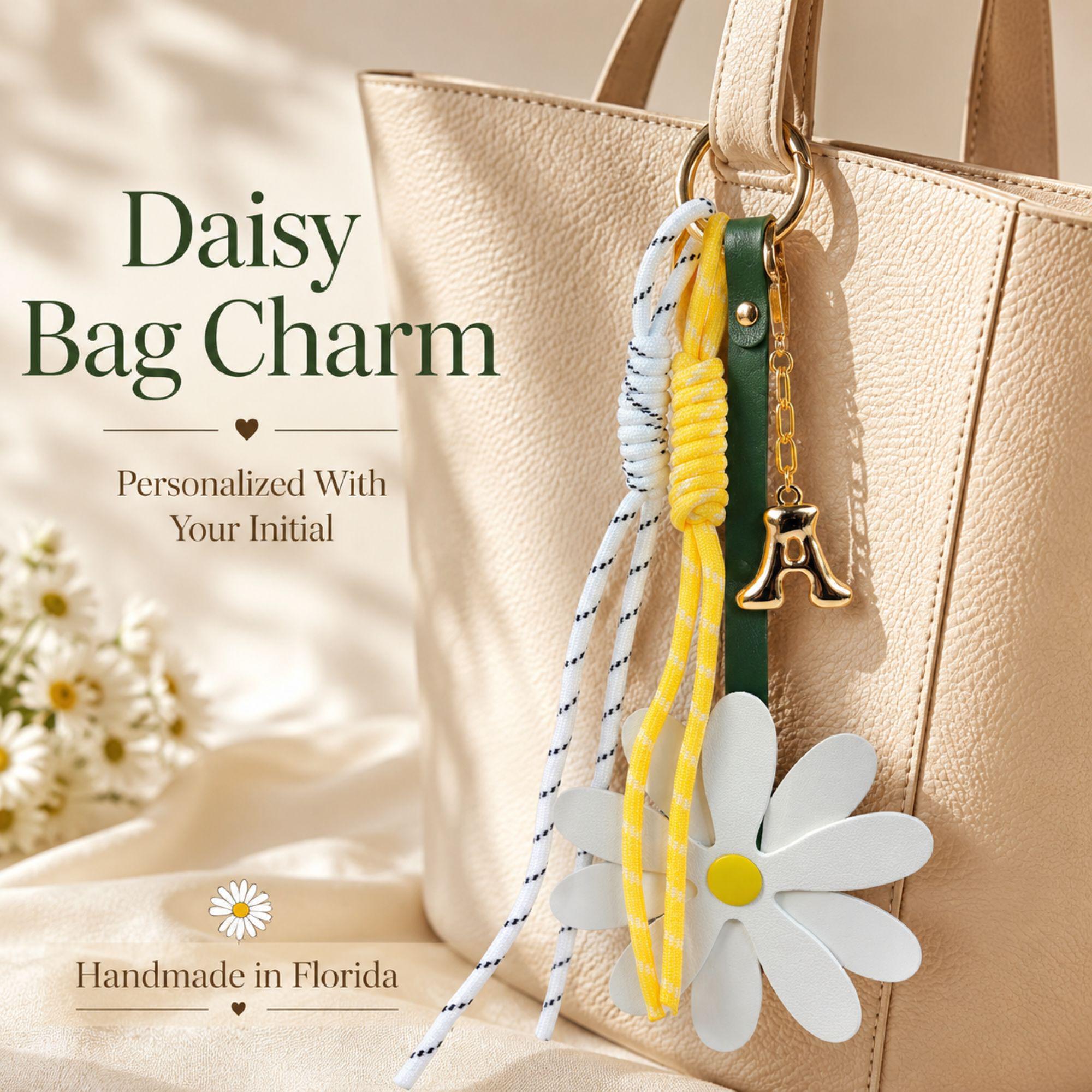 Handmade daisy bag charm with white flower charm, yellow center, personalized initial charm and decorative cord accents attached to a handbag. Flower purse charm designed for tote bags, shoulder bags, beach bags, straw bags, designer handbags and everyday purses. Trendy bag charm accessory inspired by the viral bag charm trend. Personalized handbag charm for women, teen girls, best friends and daughters. Summer bag accessory, preppy purse charm, coastal style handbag decoration and cute gift.