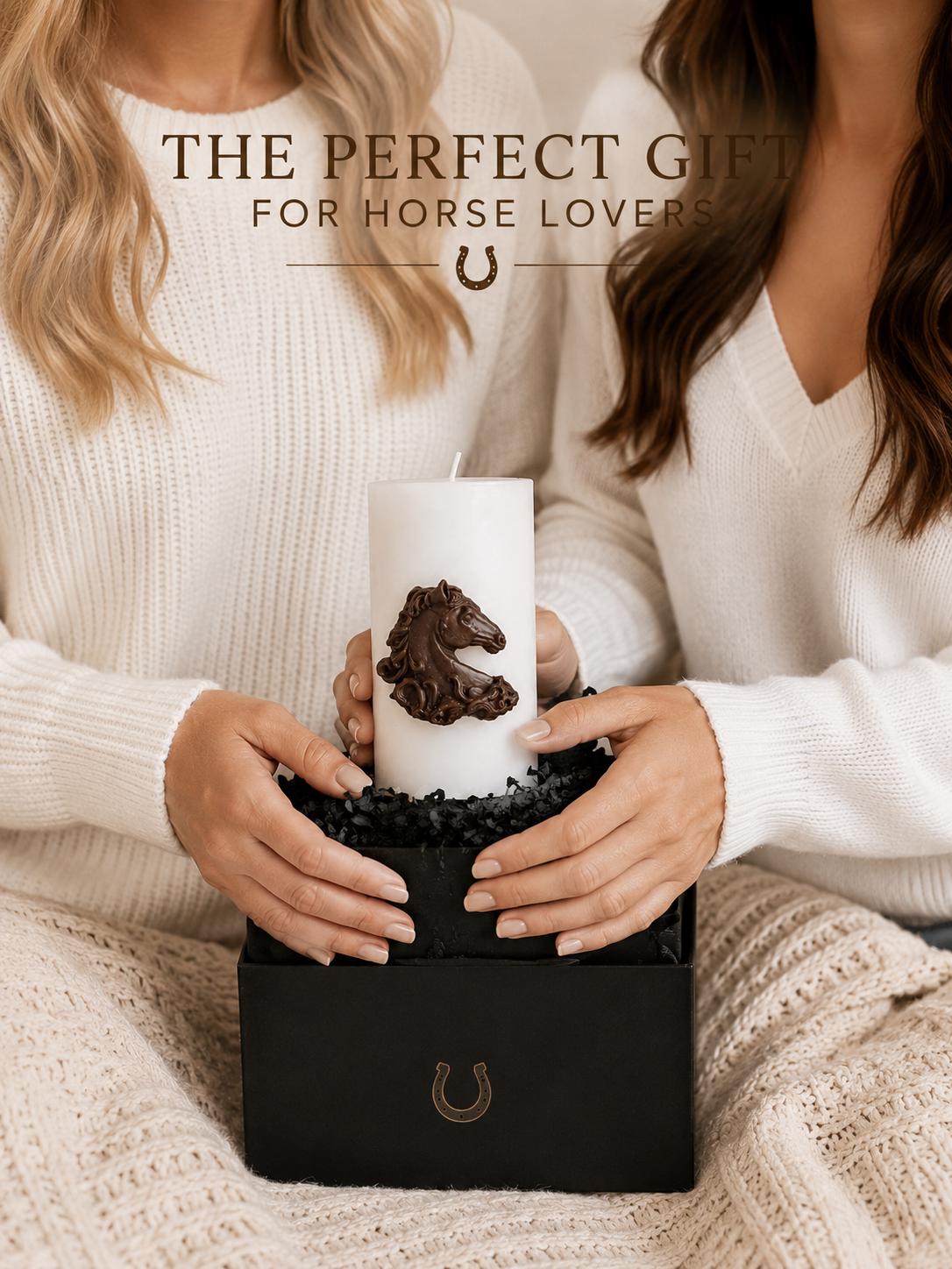 Decorative horse candle presented in an elegant black gift box, held by two women wearing white sweaters. The white pillar candle features a detailed brown horse relief, creating a thoughtful equestrian gift for horse lovers, riders, and western décor enthusiasts.