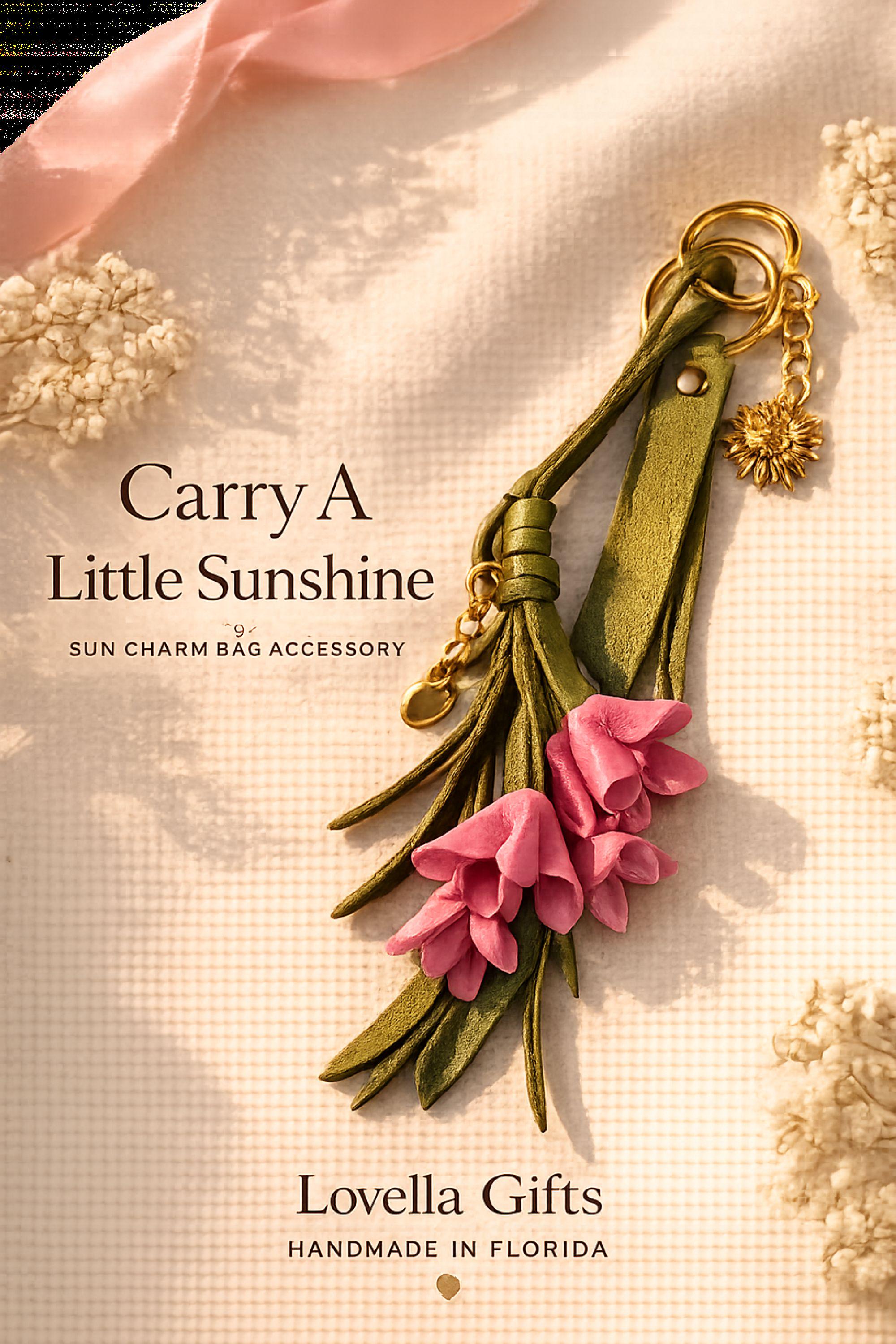 Sun Charm Bag Accessory with pink leather flowers, olive tassel, gold sun charm and premium handbag hardware on a soft beige gift background.