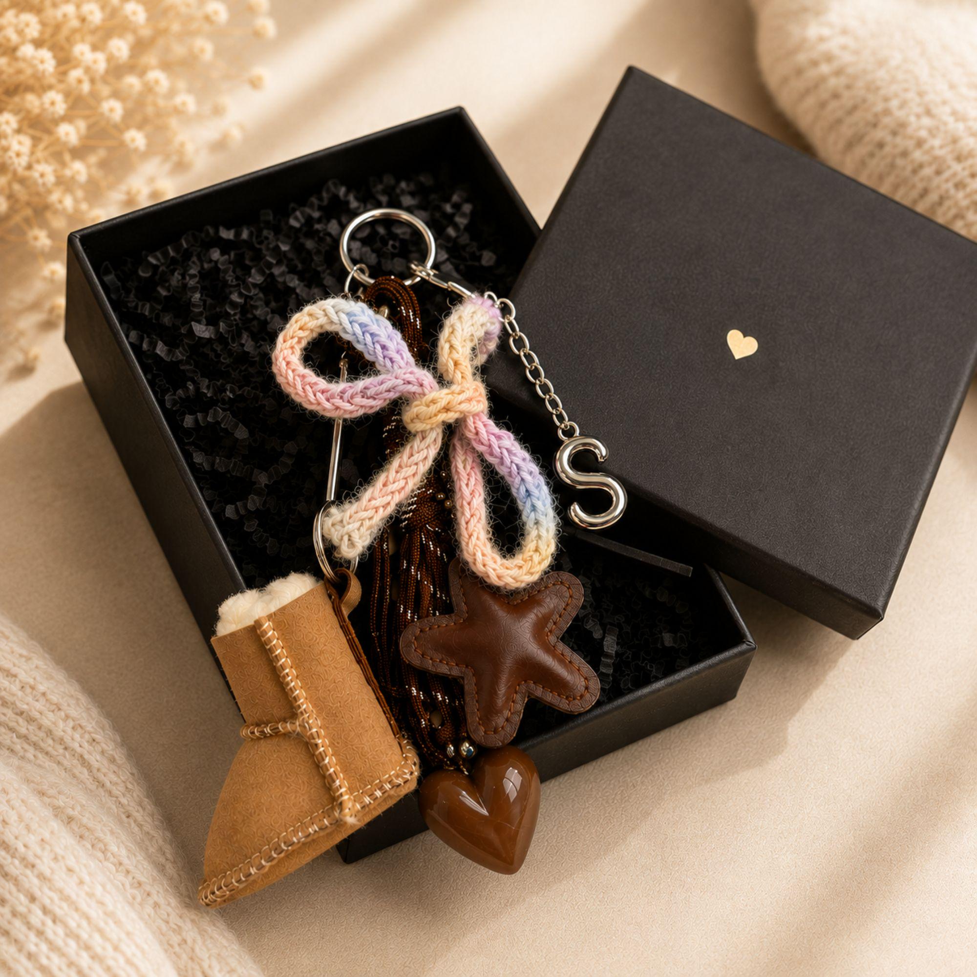 Personalized bag charm with silver initial letter, tan mini boot charm, brown leather star, glossy heart, pastel knitted bow, brown cord details and silver hardware. Cozy brown purse accessory and statement handbag charm designed for purses, totes and backpacks. Unique personalized initial keychain with layered neutral and pastel details, ideal as a cute bag accessory, backpack charm, personalized gift for her, best friend gift, sister gift or teen girl gift.