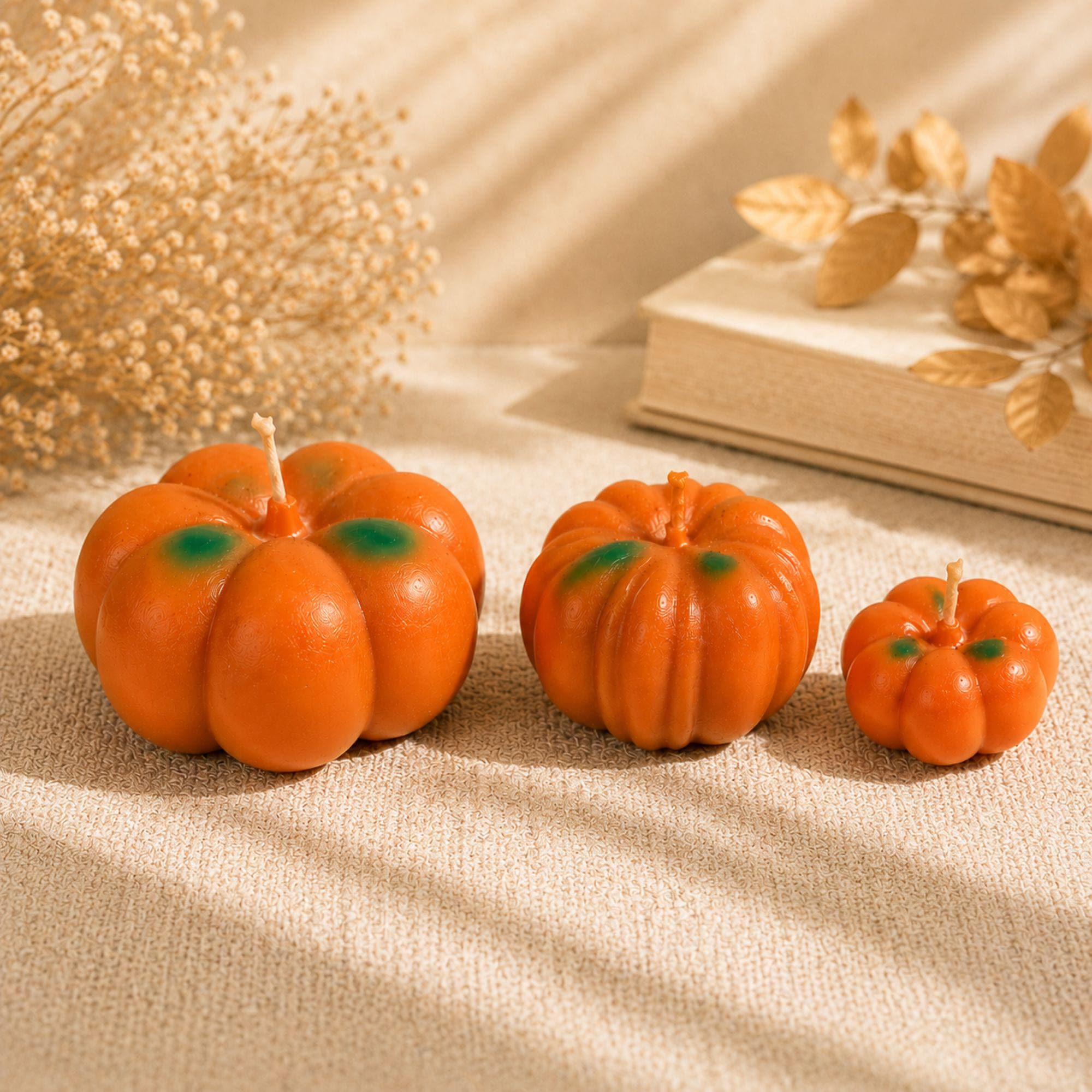 Set of 3 handmade pumpkin candles displayed with warm neutral fall decor, dried flowers, autumn leaves and cozy seasonal accents. Large, medium and small orange pumpkin shaped candles with green details create a layered fall centerpiece for Thanksgiving table decor, mantel styling, coffee table decor and harvest displays. Pumpkin Pie scented candles add a cozy autumn touch to seasonal decorating.