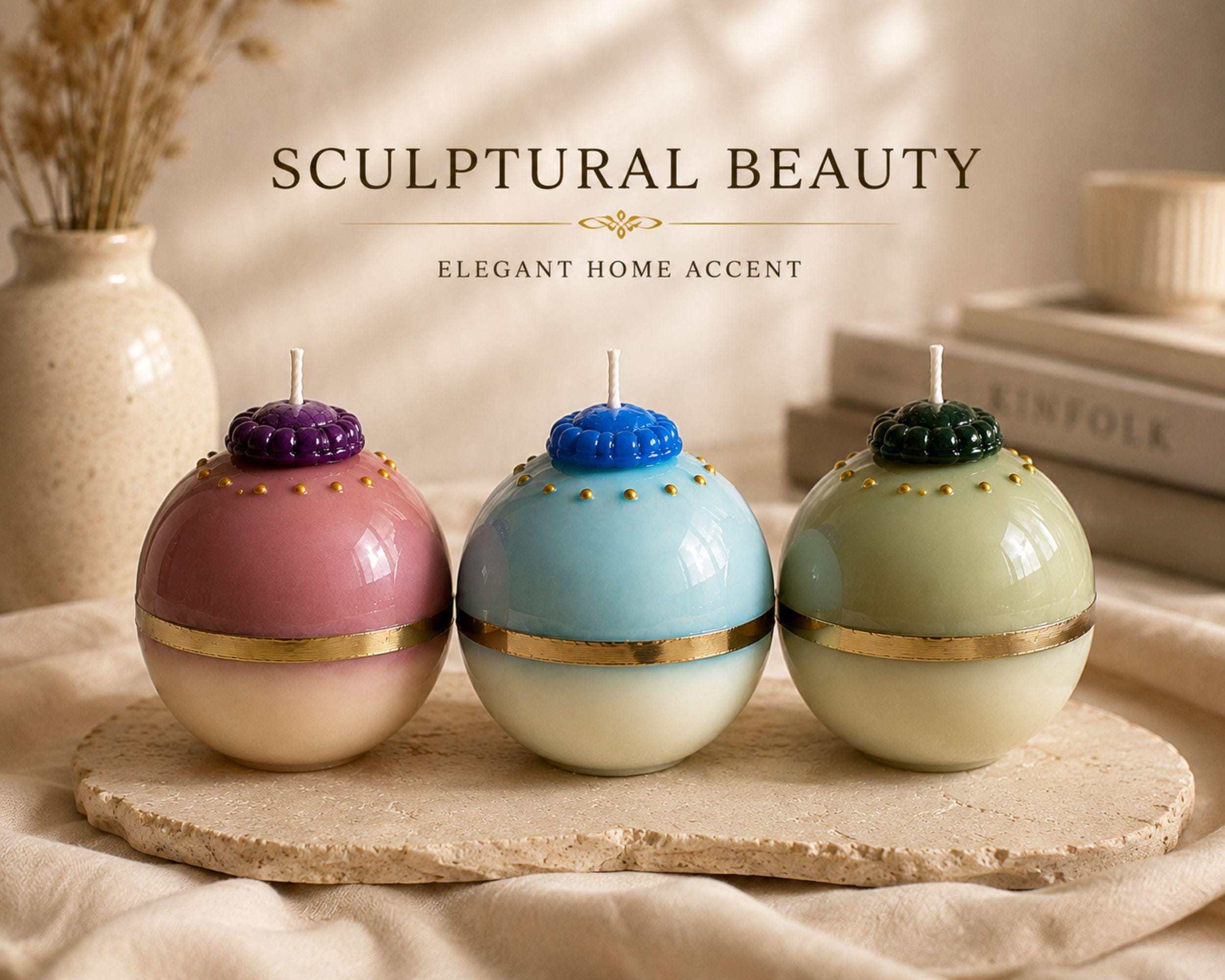 Three handmade sculptural sphere candles styled as elegant home decor in blush pink, aqua blue and pale green with gold accents and ivory bases. Artistic decorative candles for coffee table decor, shelf styling, living room accents and modern statement home decor.